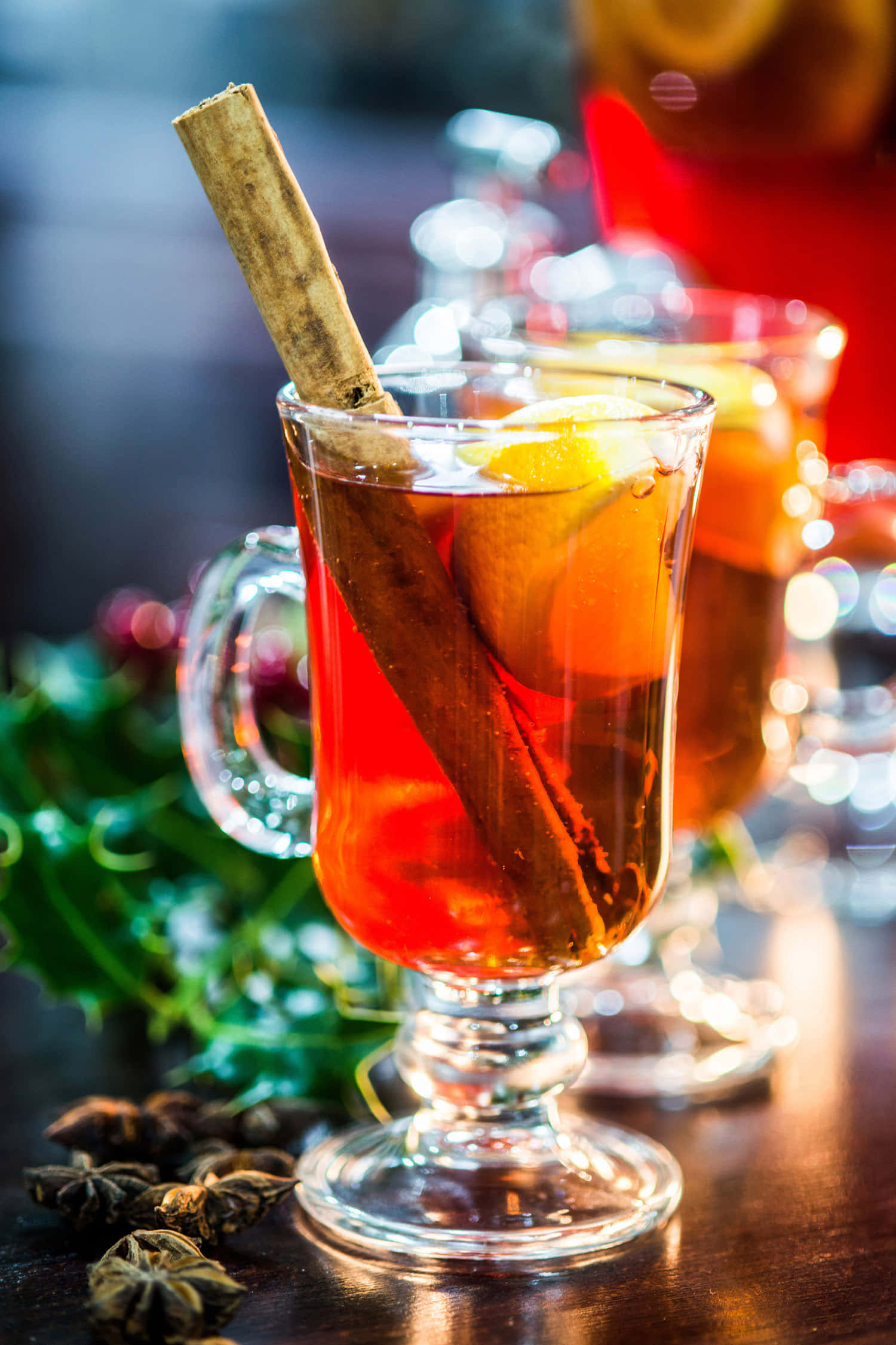 Winter Drinks 桌布 壁紙 — 一杯冒著熱氣的香料熱紅酒，配以肉桂棒和橙片，在木桌上散發溫暖的光芒。