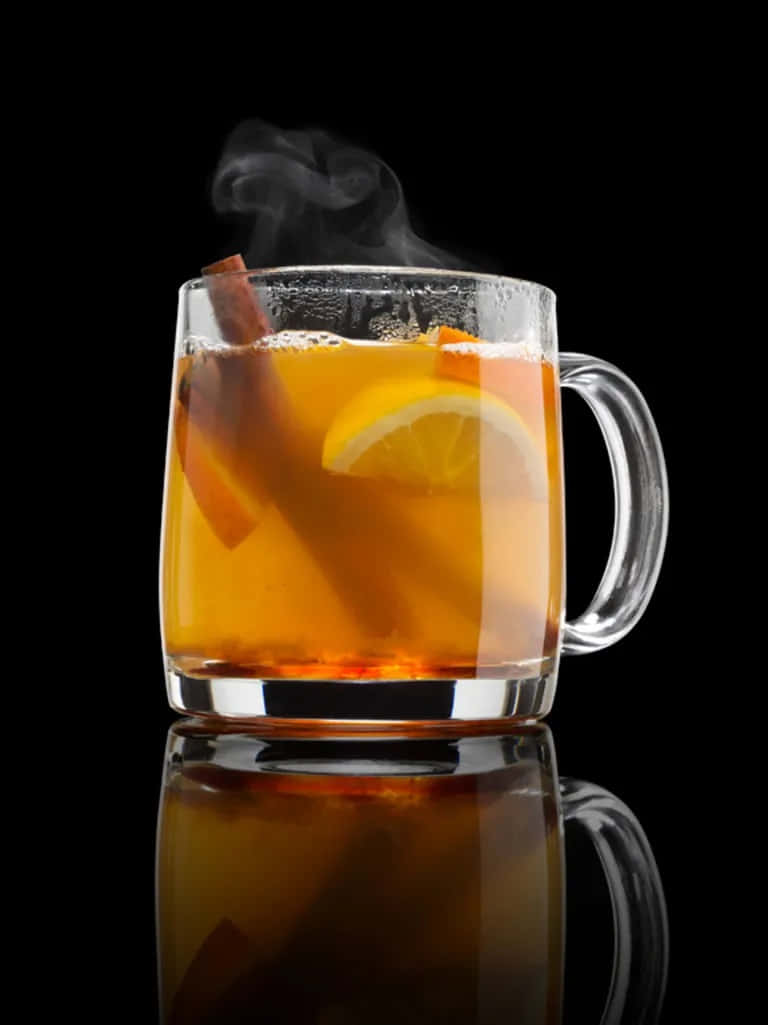 Winter Drinks 桌布 壁紙 — 一杯冒著蒸氣的玻璃杯裝香料蘋果酒，配以肉桂棒和檸檬片，在黑色反光表面上溫暖地發光。