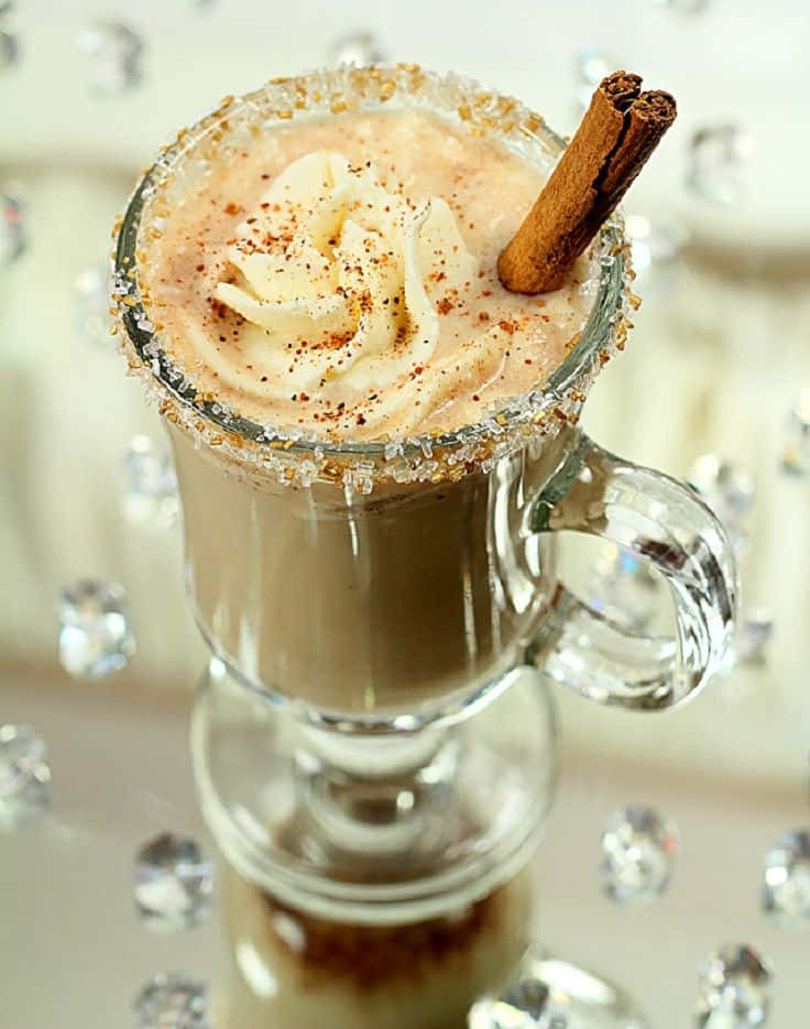 Winter Drinks 桌布 壁紙 — 一杯奶油香料飲品，上面加上鮮奶油、肉桂棒和糖邊，放在玻璃馬克杯中，置於閃閃發光的水晶表面上。