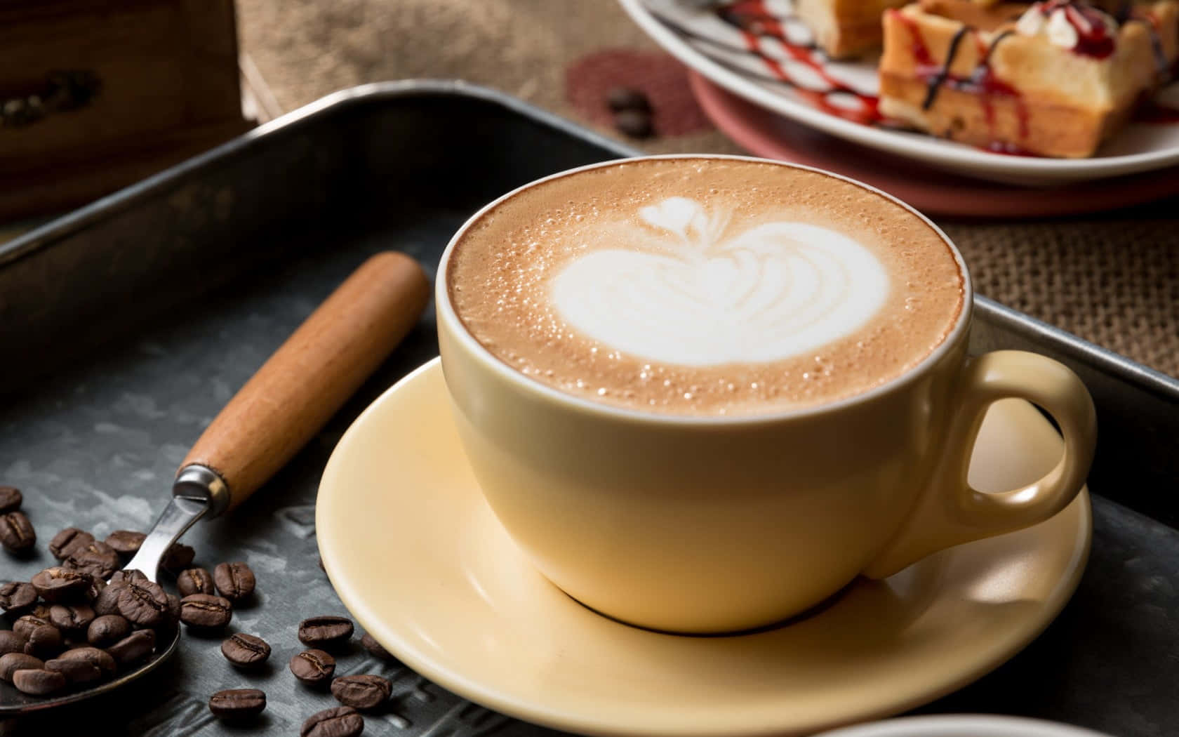 Milk And Coffee 桌布 壁紙 — 一杯奶白色咖啡拿鐵，上面有心形奶泡，放在米色杯子裡，旁邊有散落的咖啡豆和一盤窩夫。
