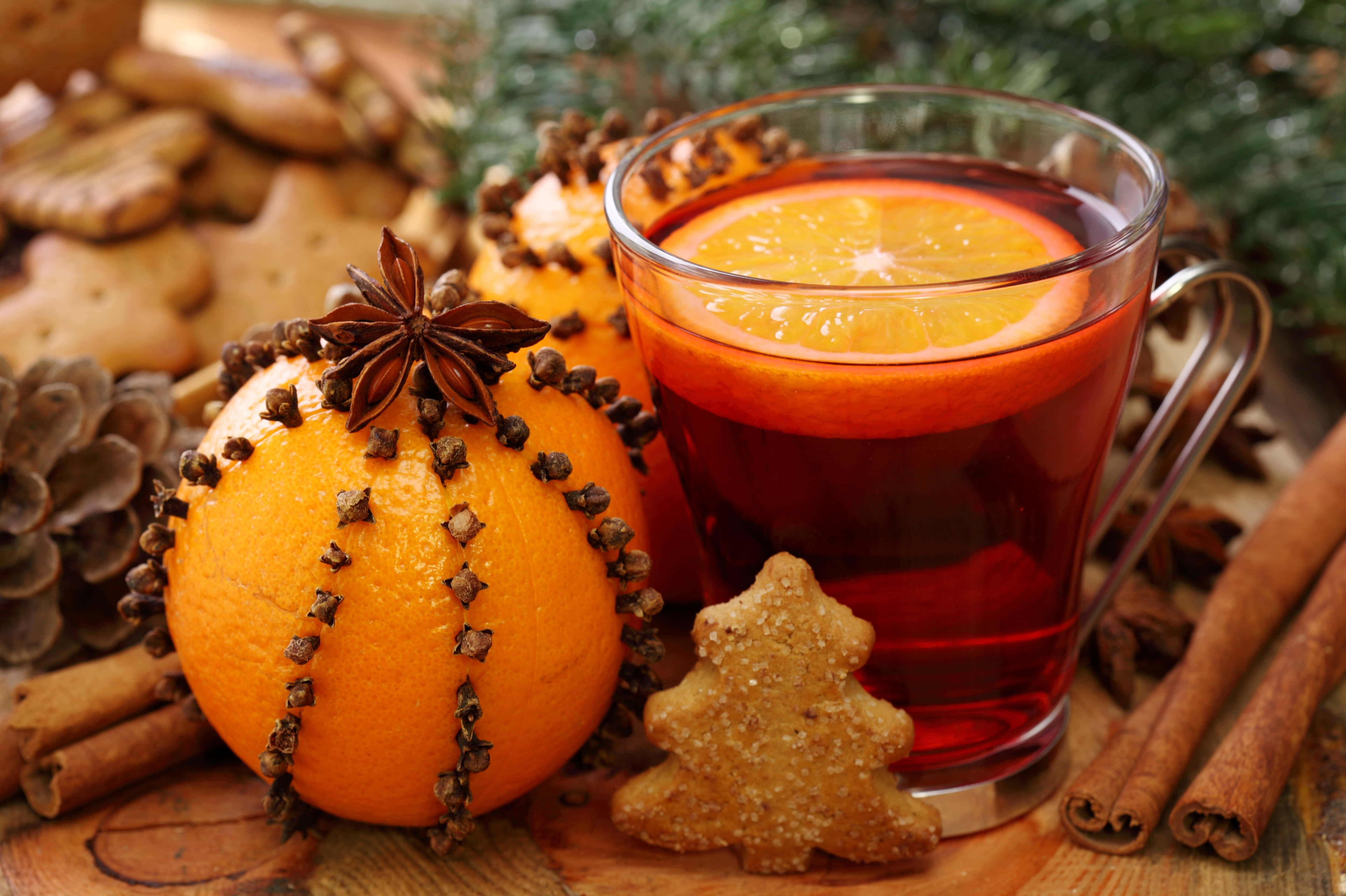 Mulled Wine 桌布 壁紙 — 一杯暖和的香料熱紅酒配橙片，旁邊放著插滿丁香橙和節日薑餅曲奇。