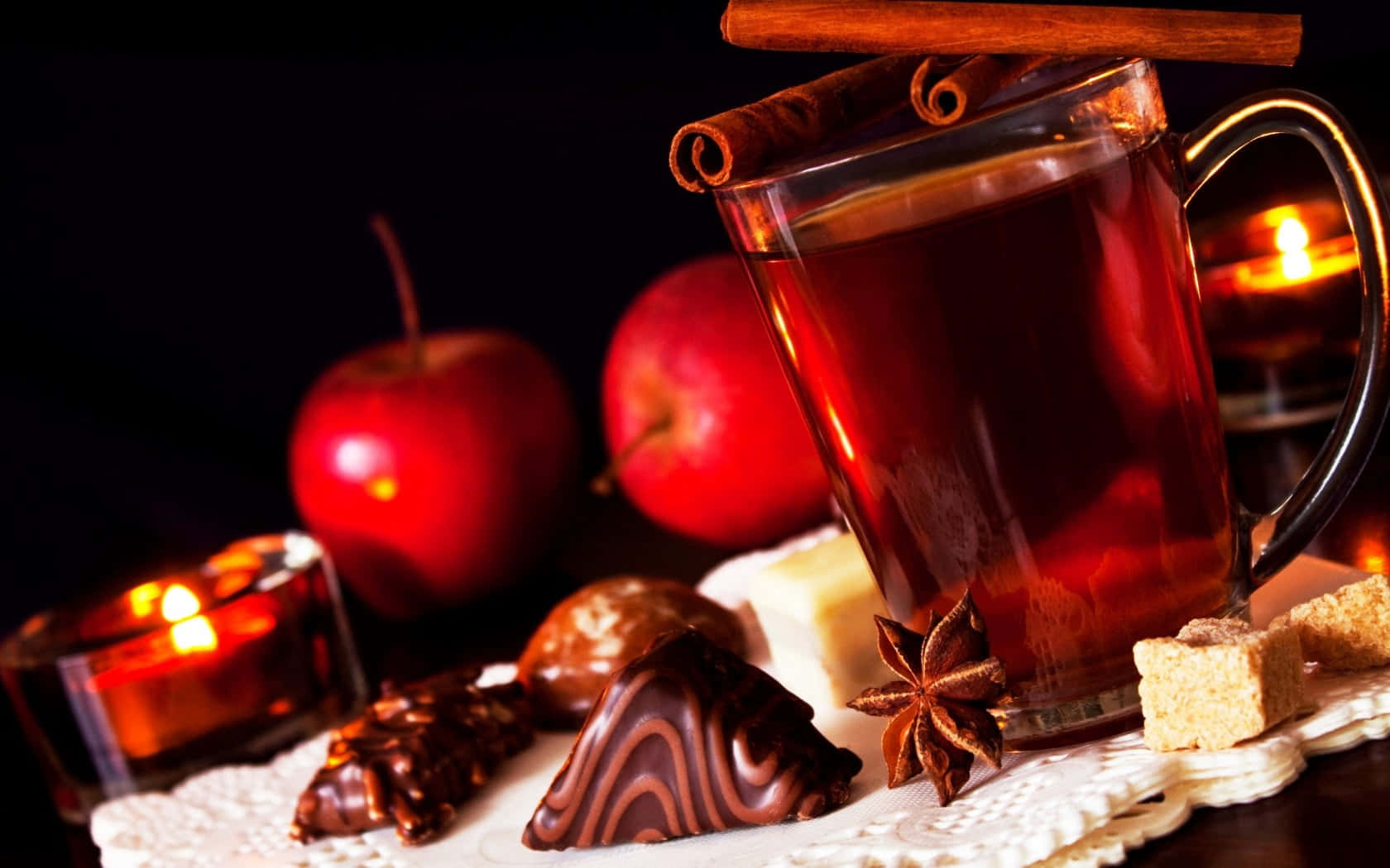 Mulled Wine 桌布 壁紙 — 一杯暖和的香料茶，配上肉桂棒和八角，放在紅蘋果和朱古力旁邊，燭光下。