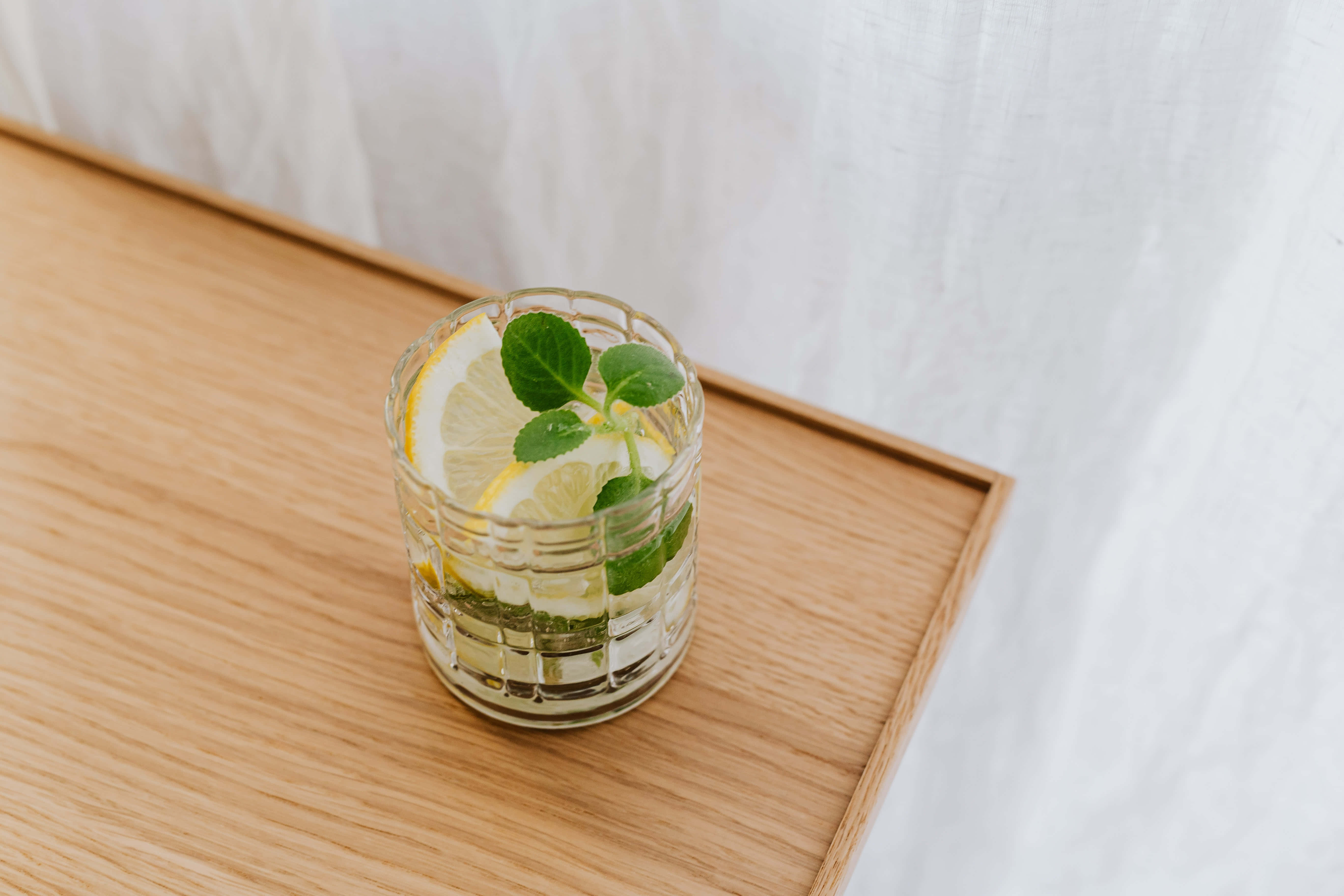 Summer Drinks 桌布 壁紙 — 一杯清爽的檸檬水配薄荷葉，放在淺色木托盤上，背景是柔軟的白色窗簾。