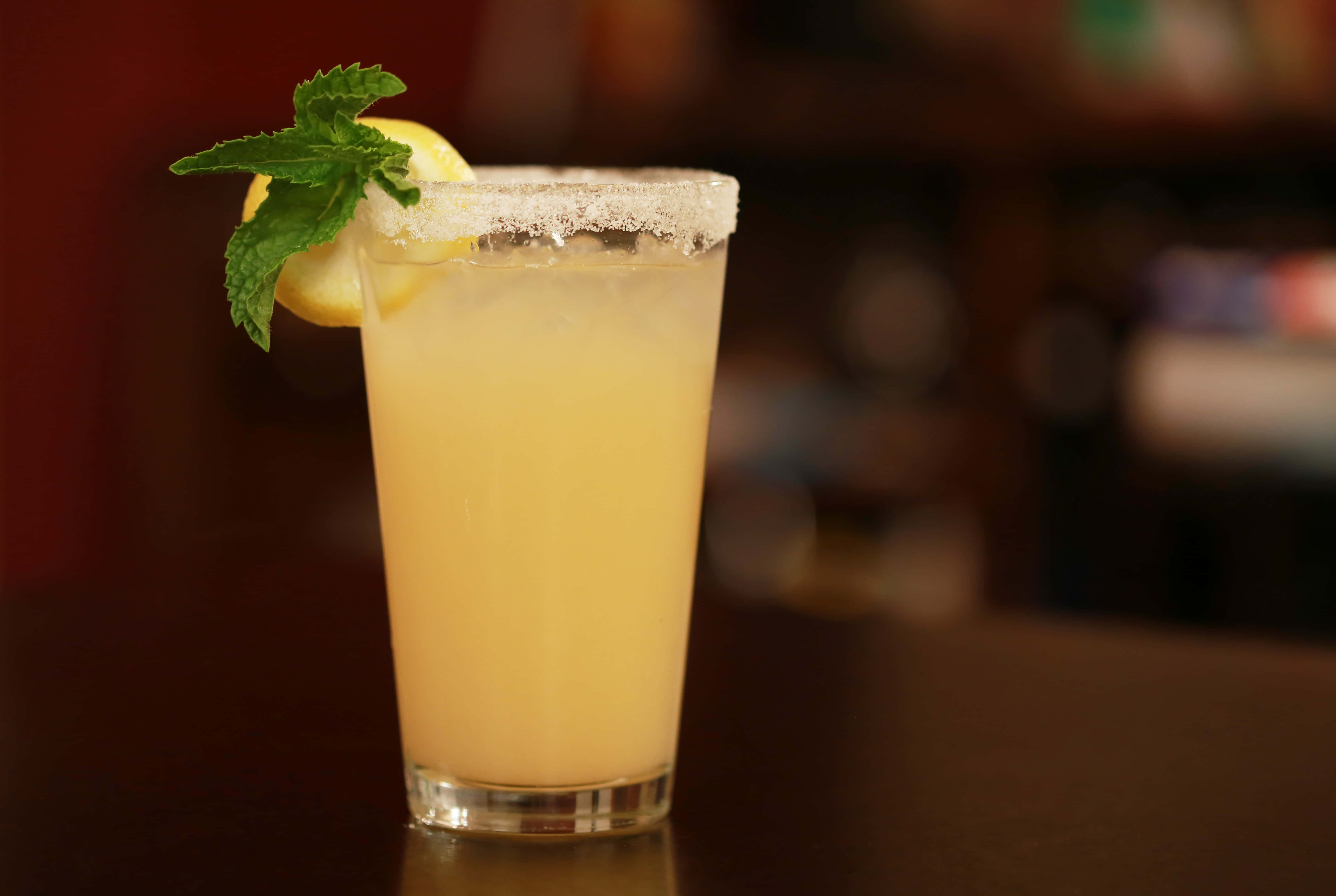 Summer Drinks 桌布 壁紙 — 一杯清爽的瑪格麗特，帶有鹽邊、檸檬角和薄荷裝飾，放在深色吧檯上。