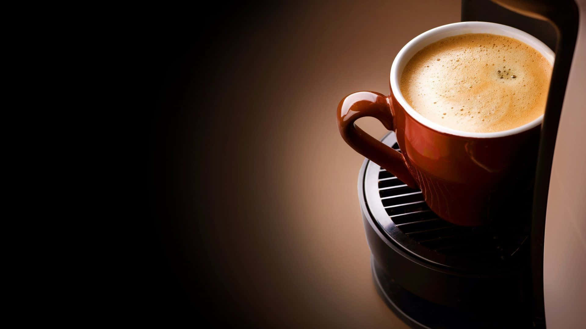 Black Coffee 桌布 壁紙 — 一杯濃郁的棕色咖啡，帶有泡沫奶泡，放在機器上，在深色漸變背景的襯托下被照亮。