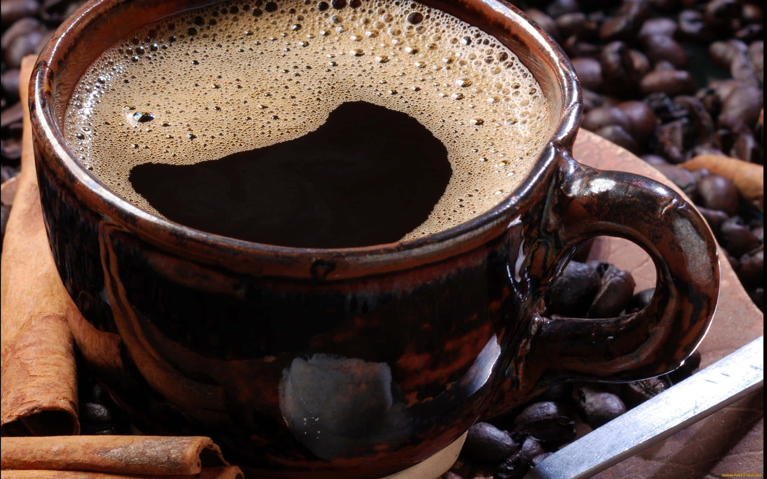 Black Coffee 桌布 壁紙 — 一杯濃郁的黑咖啡放在鄉村風格的陶瓷杯中，周圍環繞著咖啡豆和肉桂棒。