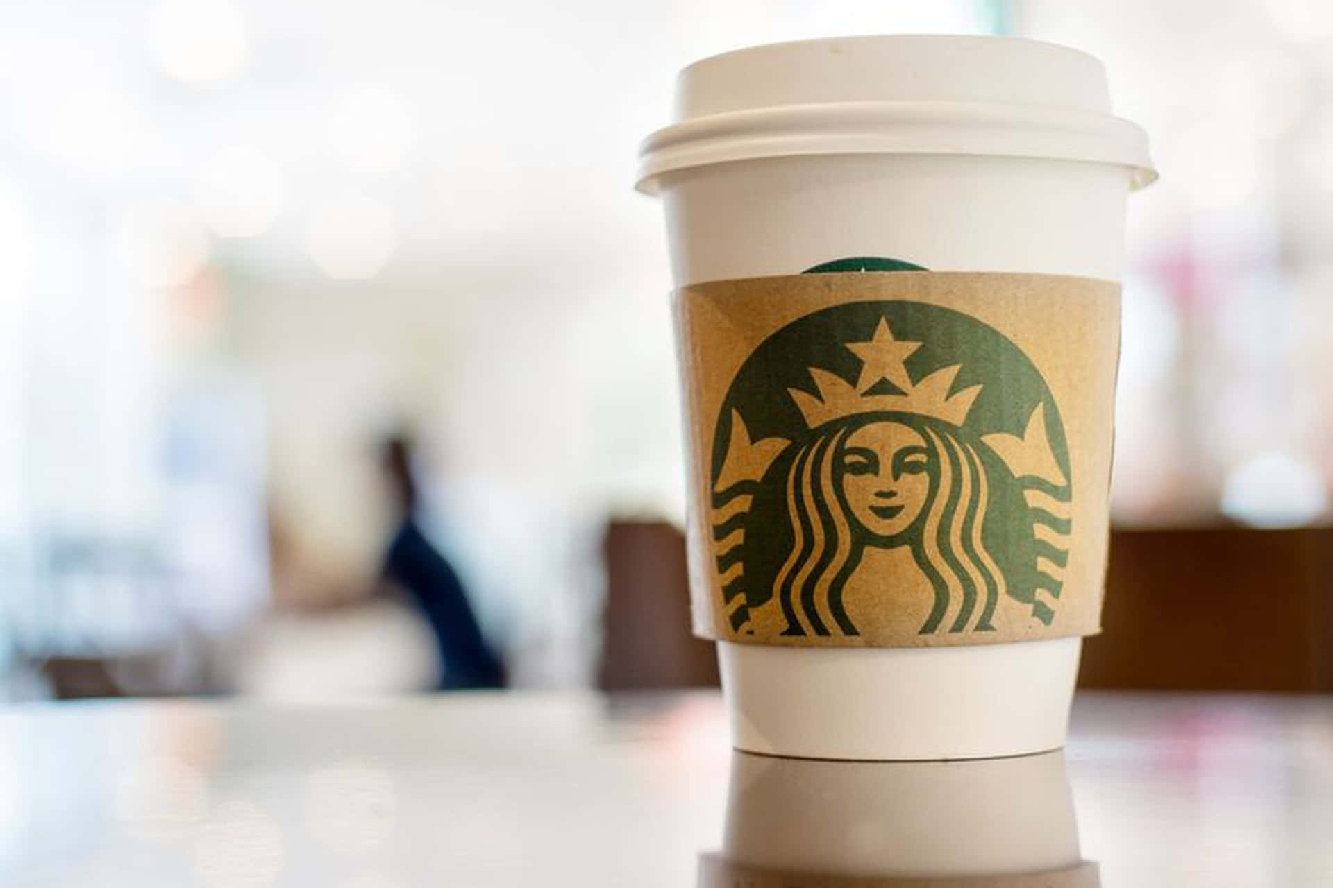 明亮咖啡廳反射桌上的Starbucks咖啡杯。