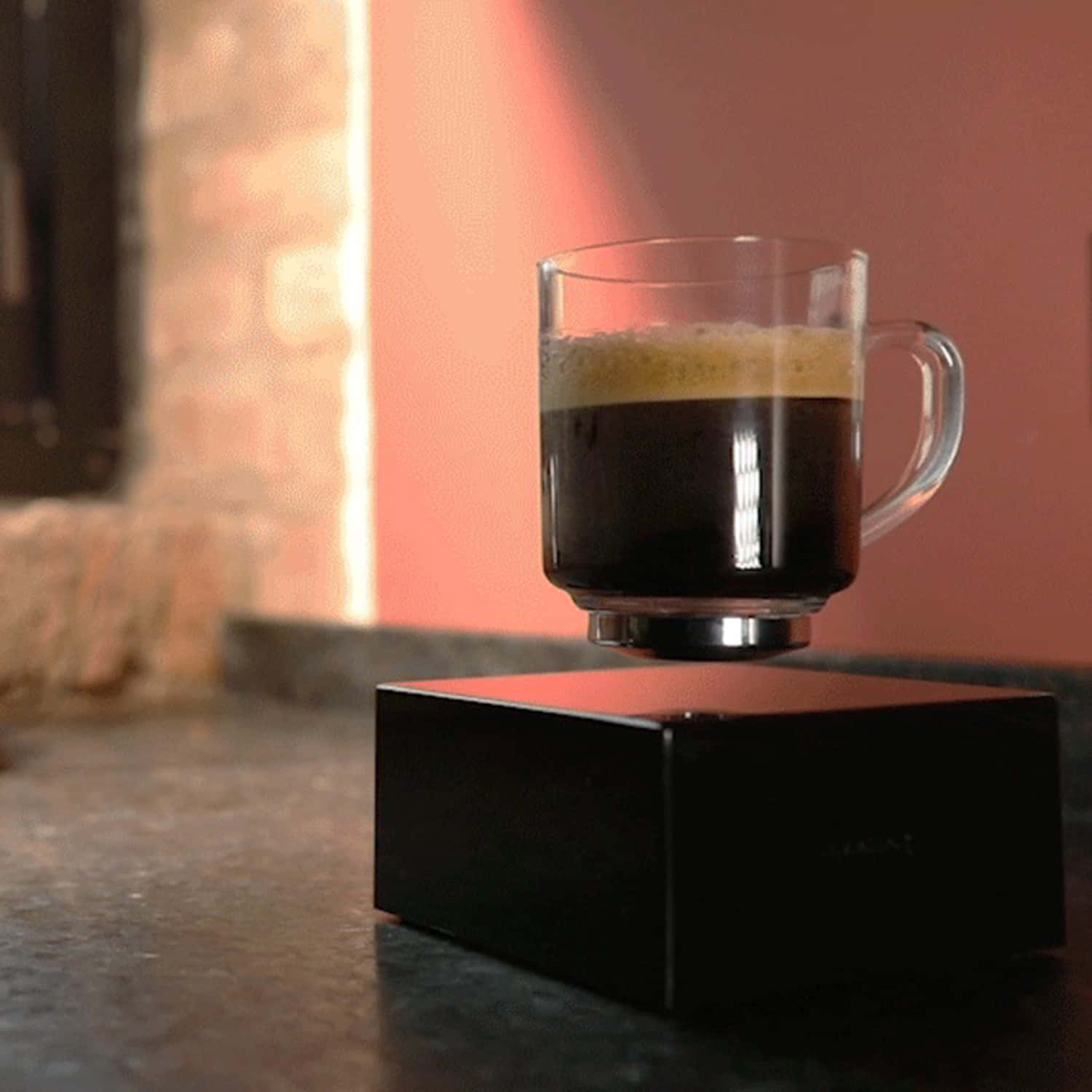 Coffee Cup 桌布 壁紙 — 一杯玻璃杯裝的濃縮咖啡磁浮在一個時尚的黑色懸浮底座上，置於深色檯面。