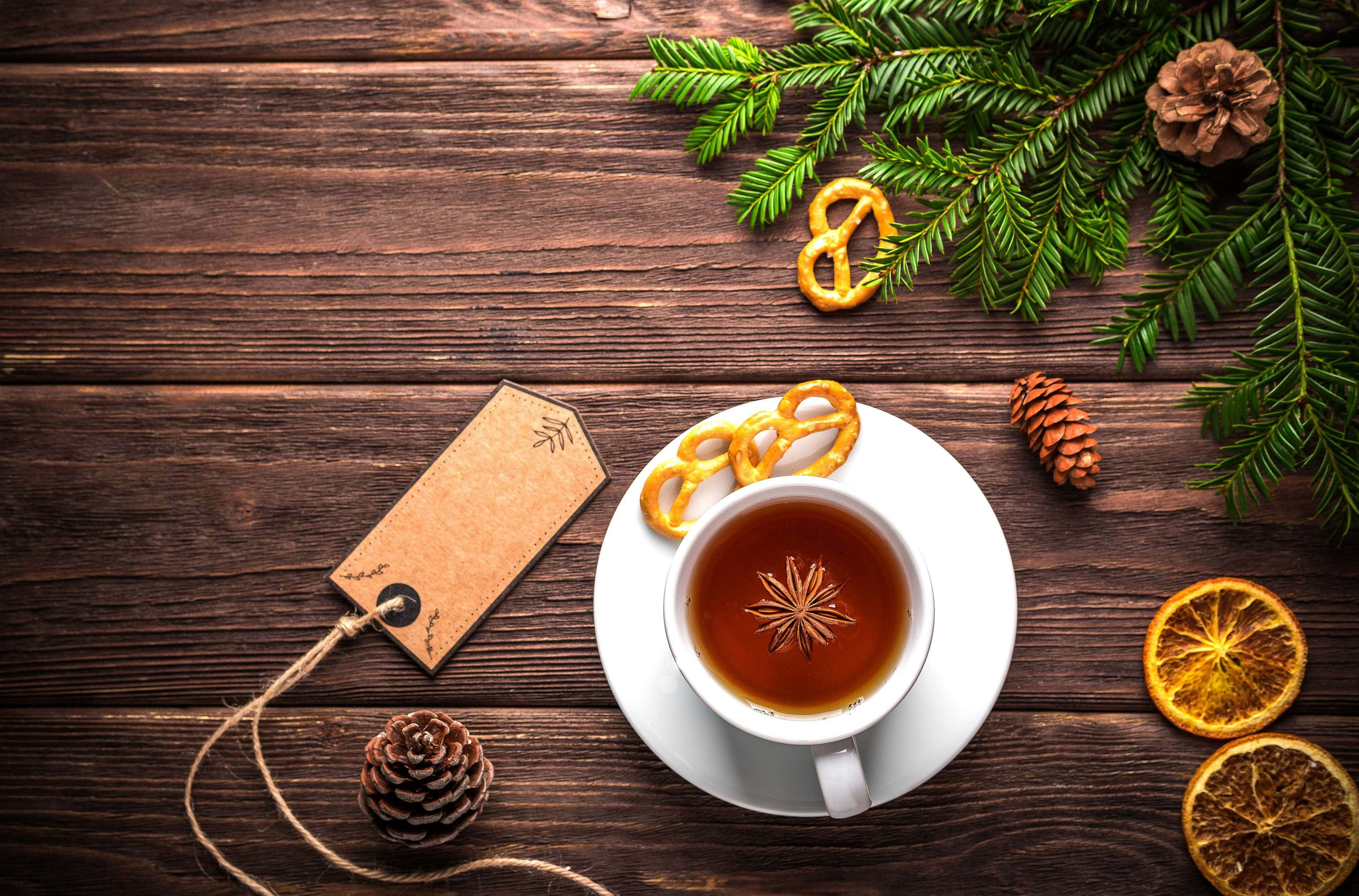 Rustic Christmas 桌布 壁紙 — 一杯舒適的香料茶，配上八角，漂浮在質樸的木桌上，旁邊有松枝、椒鹽脆餅和乾橙片。