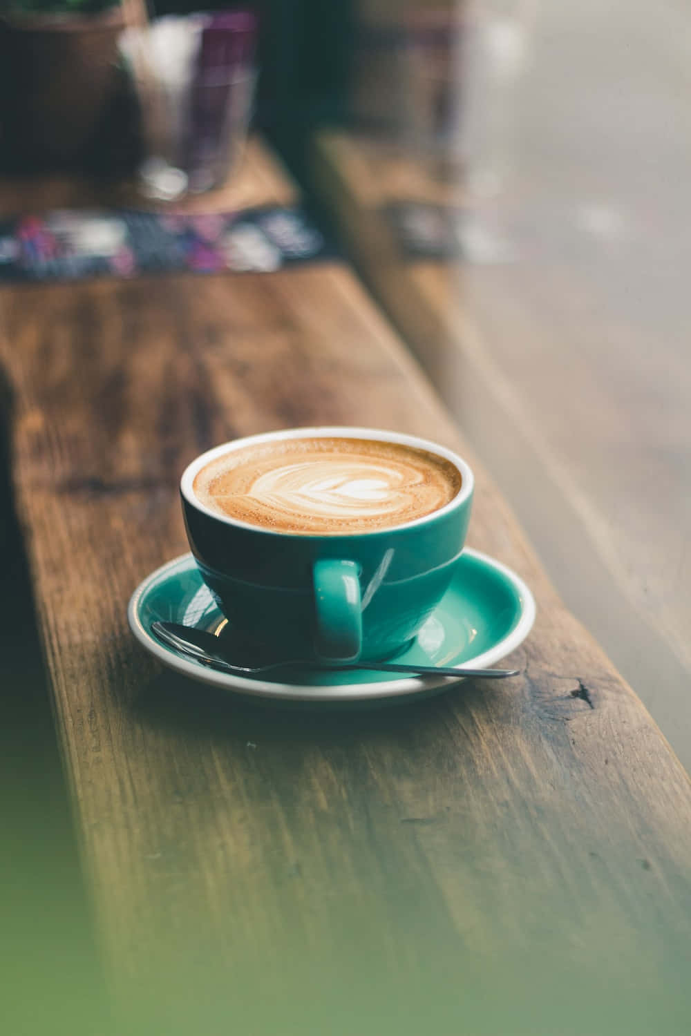 Coffee Cup 桌布 壁紙 — 一杯藍綠色嘅拉花咖啡放喺鄉村風格嘅木枱上，伴隨柔和自然光。