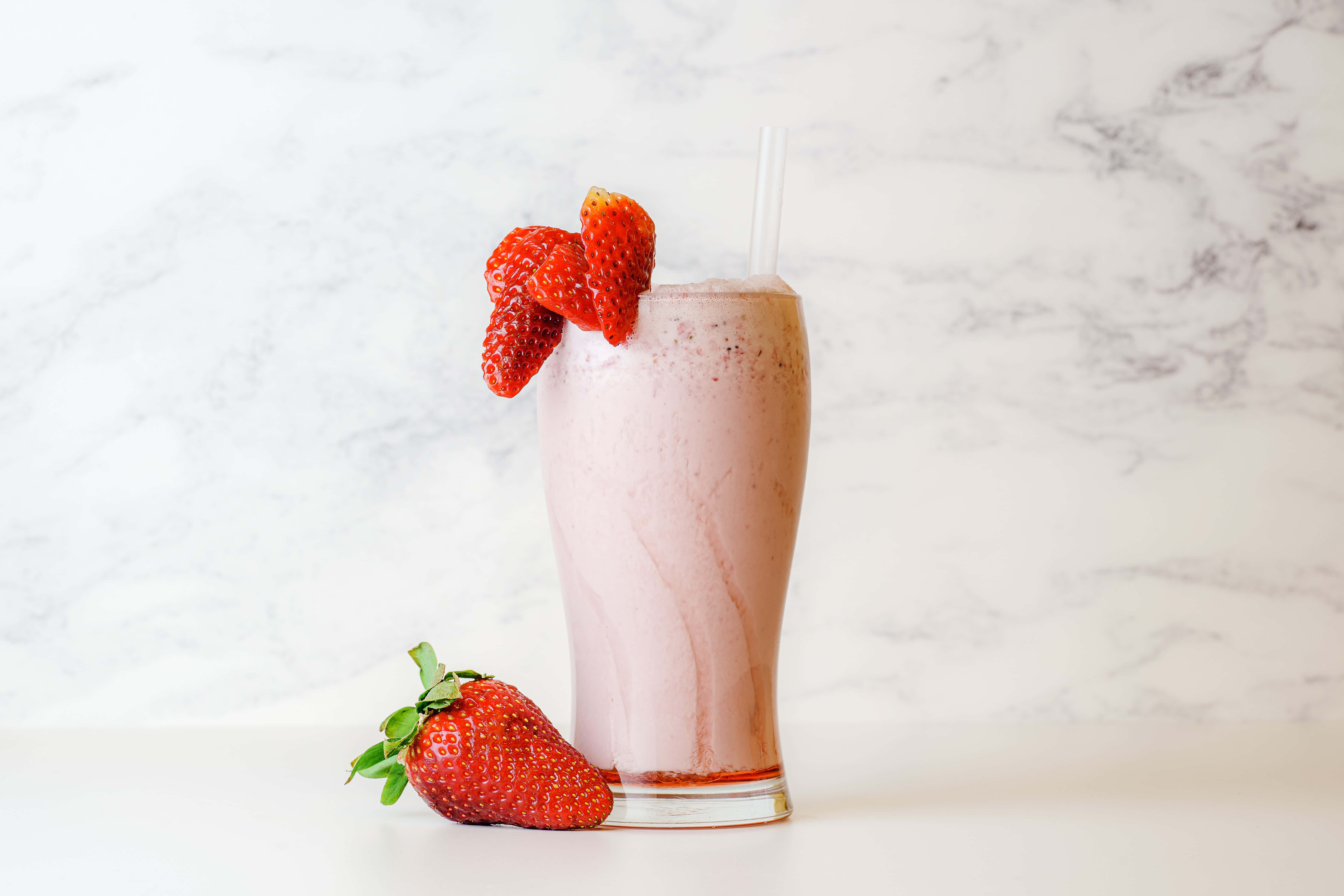 Summer Drinks 桌布 壁紙 — 一杯高身粉紅草莓奶昔，以新鮮草莓點綴，襯以白色雲石背景。