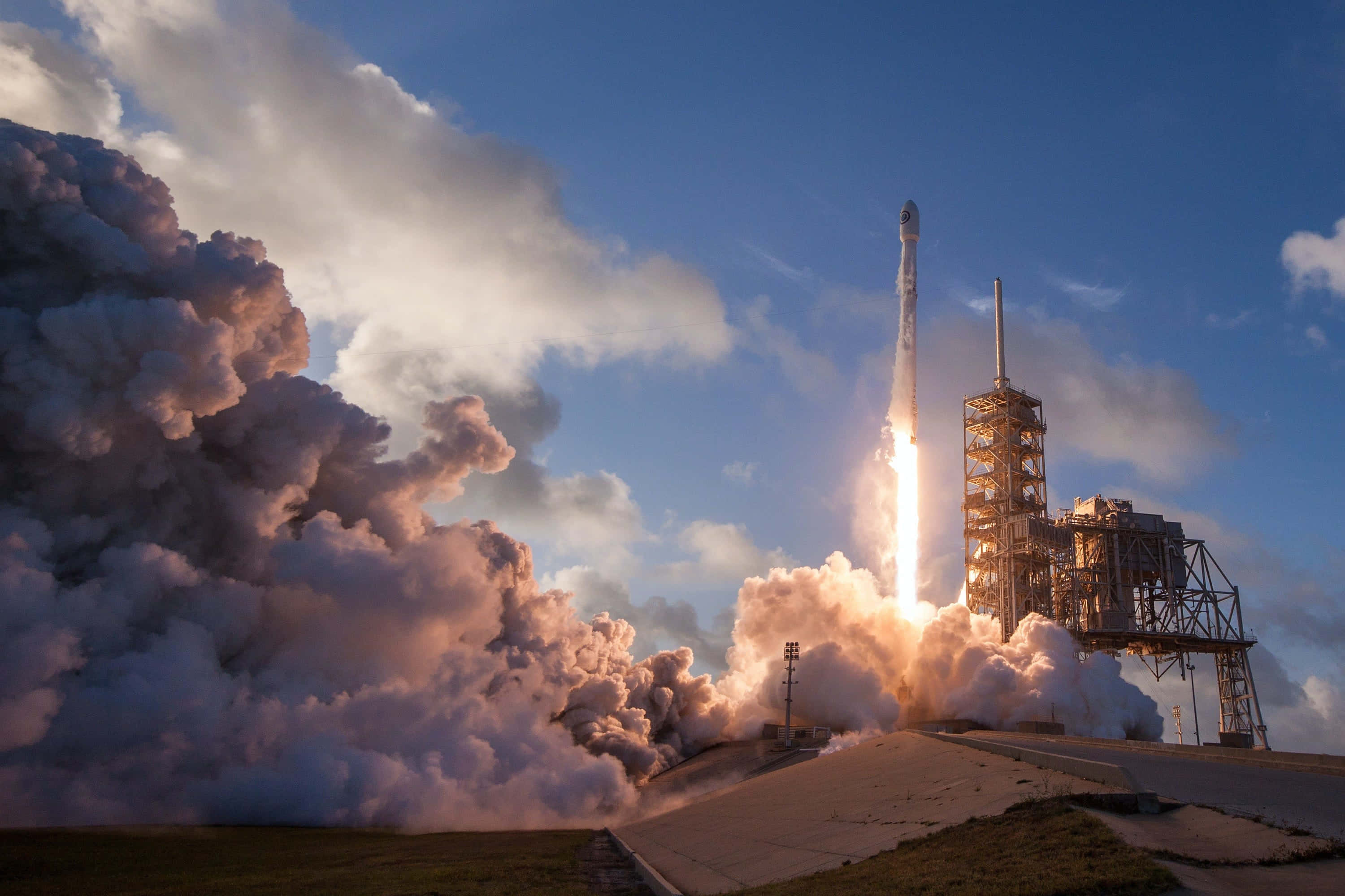 Space Exploration 桌布 壁紙 — 一枚火箭強力地穿過藍天，在發射台留下熾熱的廢氣和滾滾濃煙的痕跡。