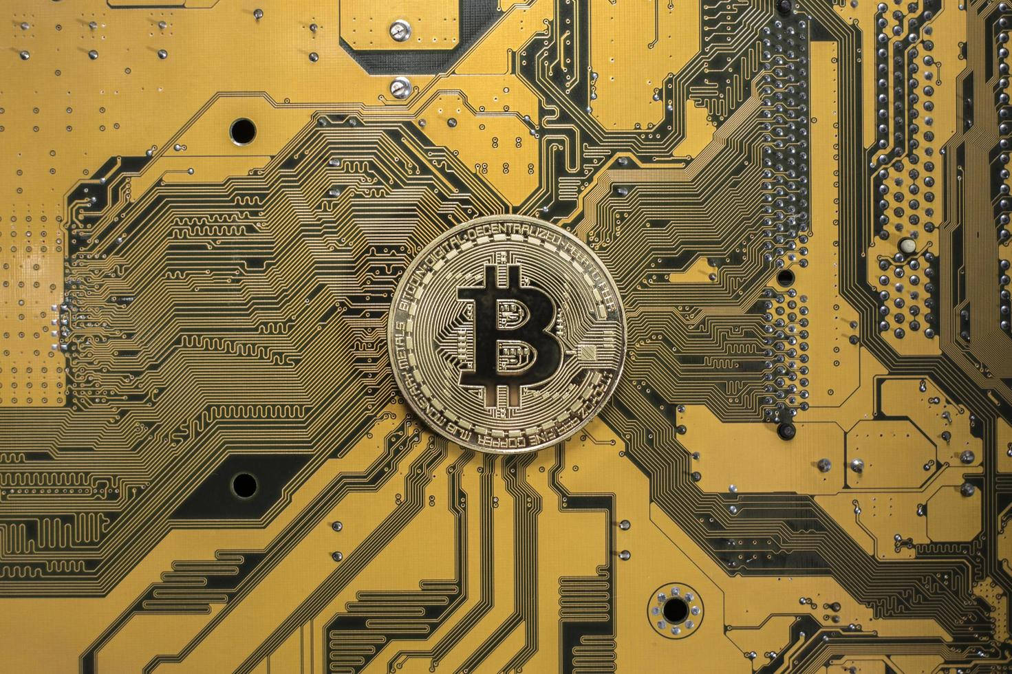 黃色電路板上的一枚金色比特幣硬幣。 — 比特幣 壁紙