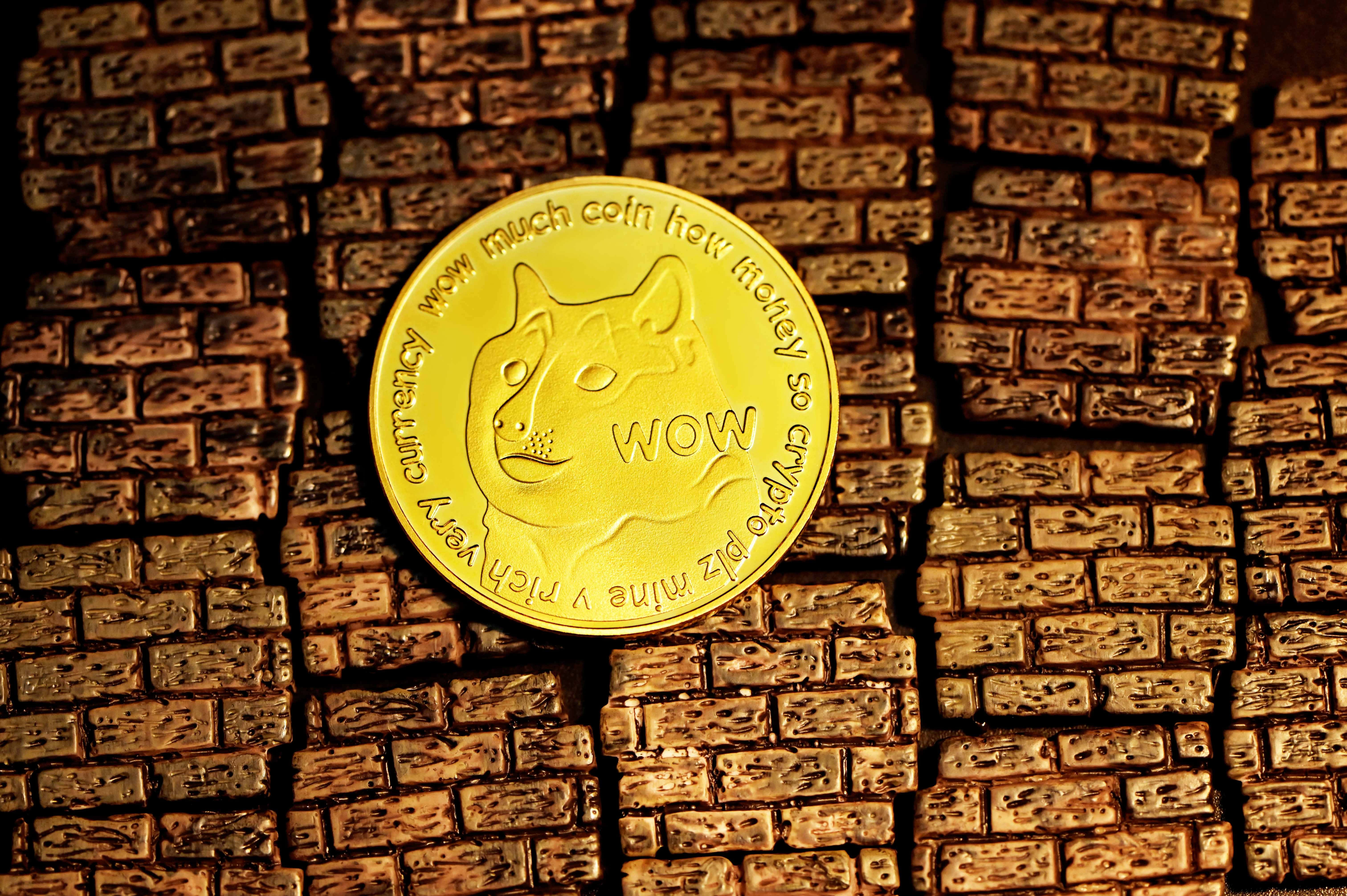 Dogecoin 桌布 壁紙 — 一枚金色狗狗幣放在有紋理的磚牆上，在溫暖的燈光下突顯其雕刻文字和柴犬臉。