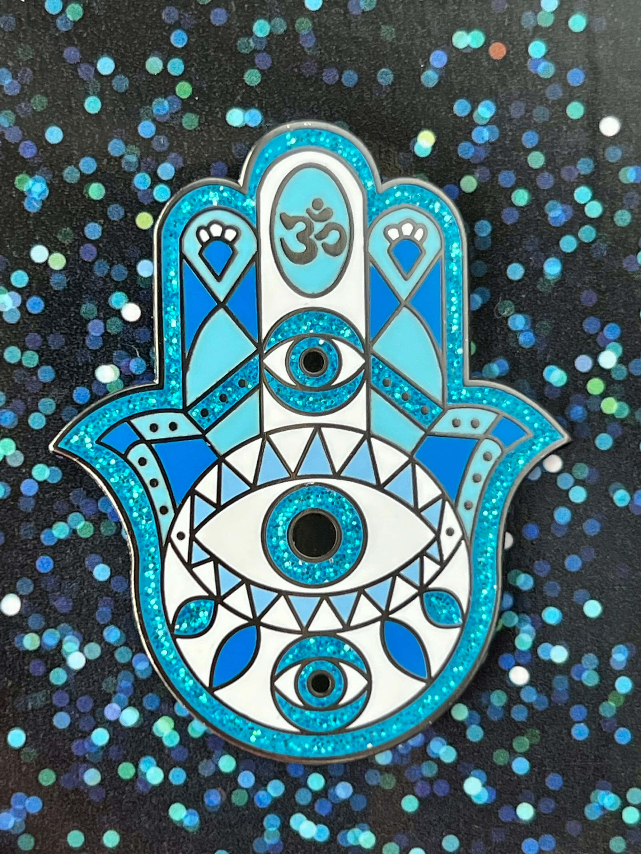 Hamsa 桌布 壁紙 — 一枚閃閃發光的藍白漢莎手形別針，帶有三隻眼睛和一個嗡（Om）符號，置於閃爍的深色背景上。