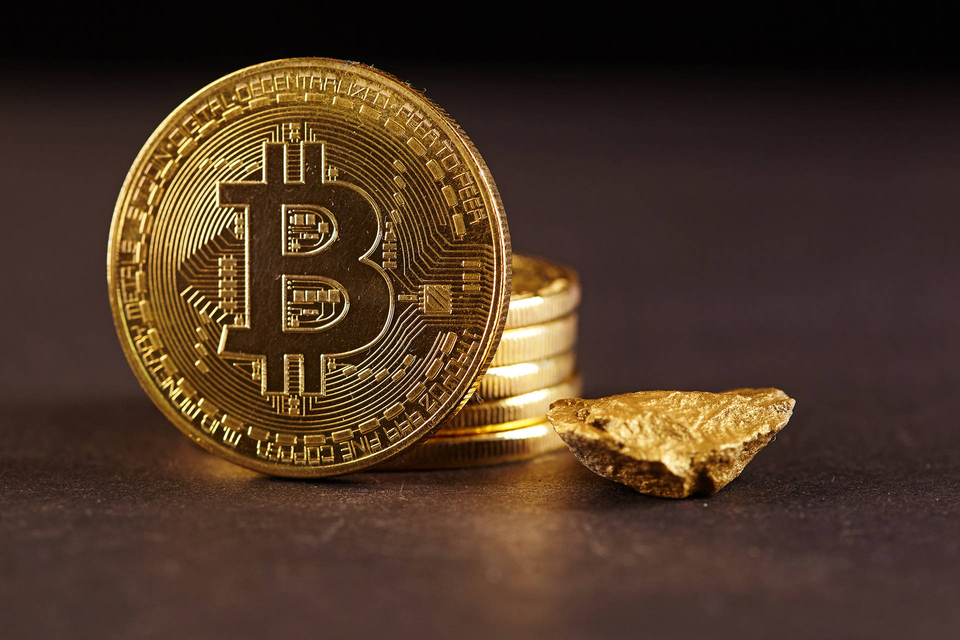 一枚比特幣硬幣和金塊，代表數位和傳統財富。 — 比特幣 壁紙