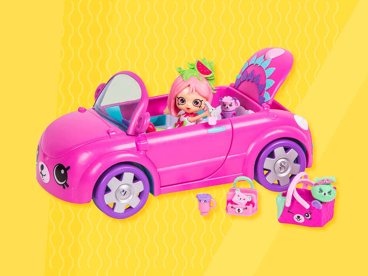 Shopkins 桌布 壁紙 — 一架亮粉紅色玩具開篷車，裏面有公仔和毛絨寵物，放在黃色波浪背景上，附有配件。