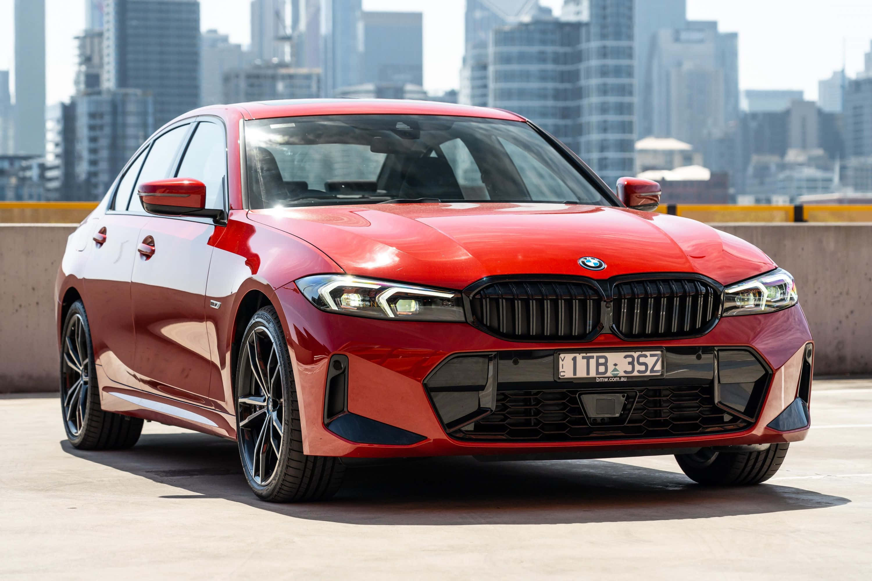 Bmw 3 Series 桌布 壁紙 — 一架亮紅色BMW 3系房車停泊在混凝土屋頂上，背景是現代城市天際線。
