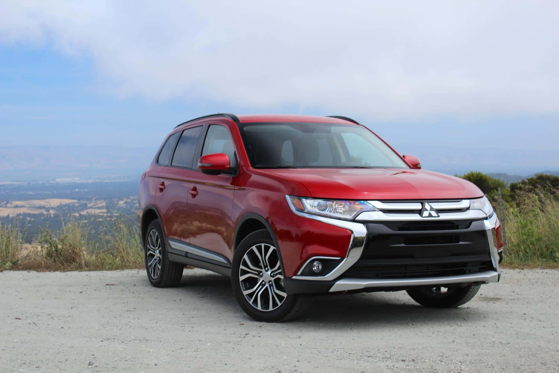 Mitsubishi Asx 桌布 壁紙 — 一架亮紅色三菱Outlander SUV停泊在碎石觀景點，俯瞰煙霧瀰漫的山谷和遠山，天空多雲。