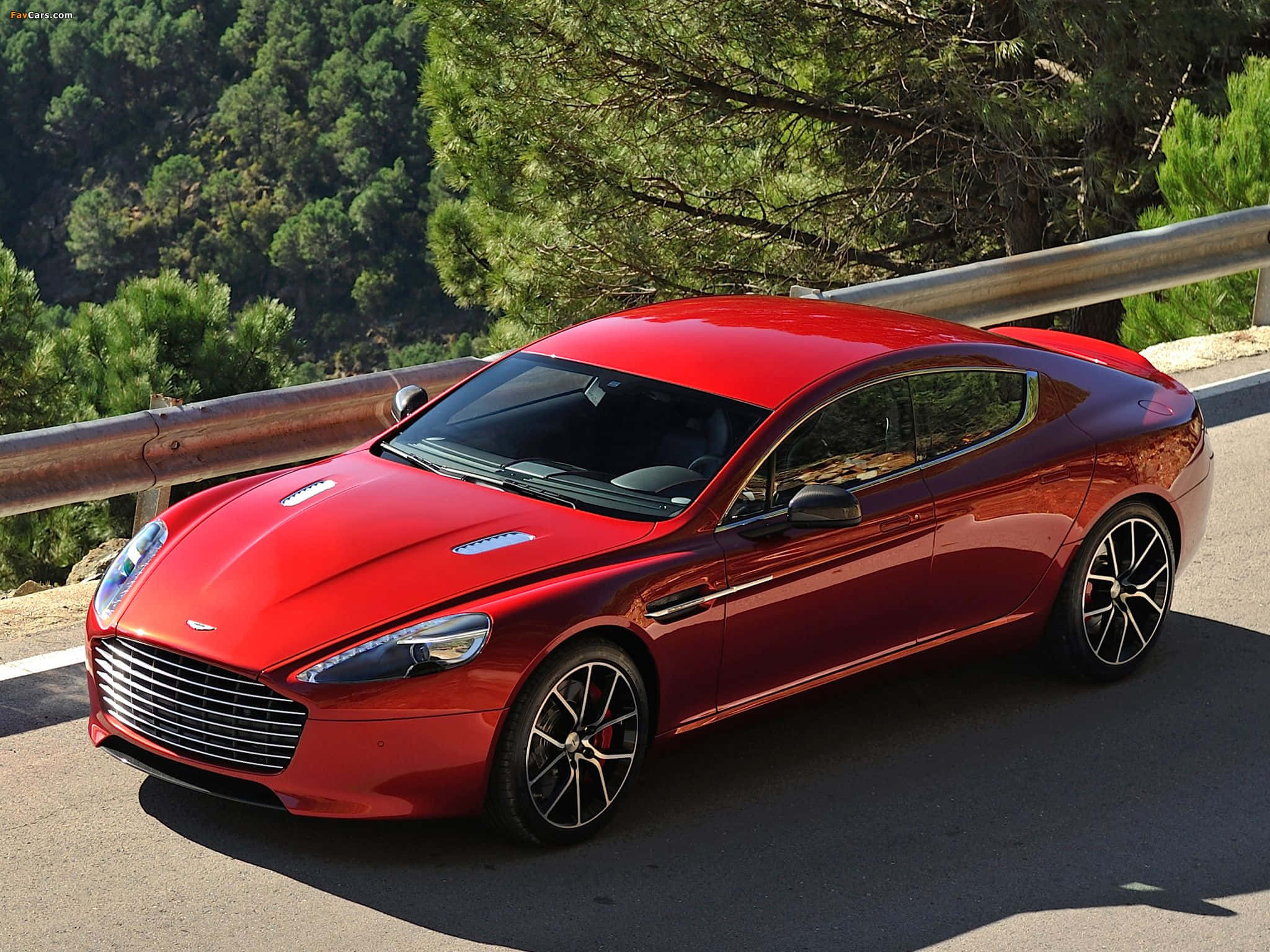 Aston Martin Rapide S 桌布 壁紙 — 一架亮紅色嘅Aston Martin跑車停泊喺蜿蜒嘅山路，旁邊有茂密嘅綠樹同金屬護欄。