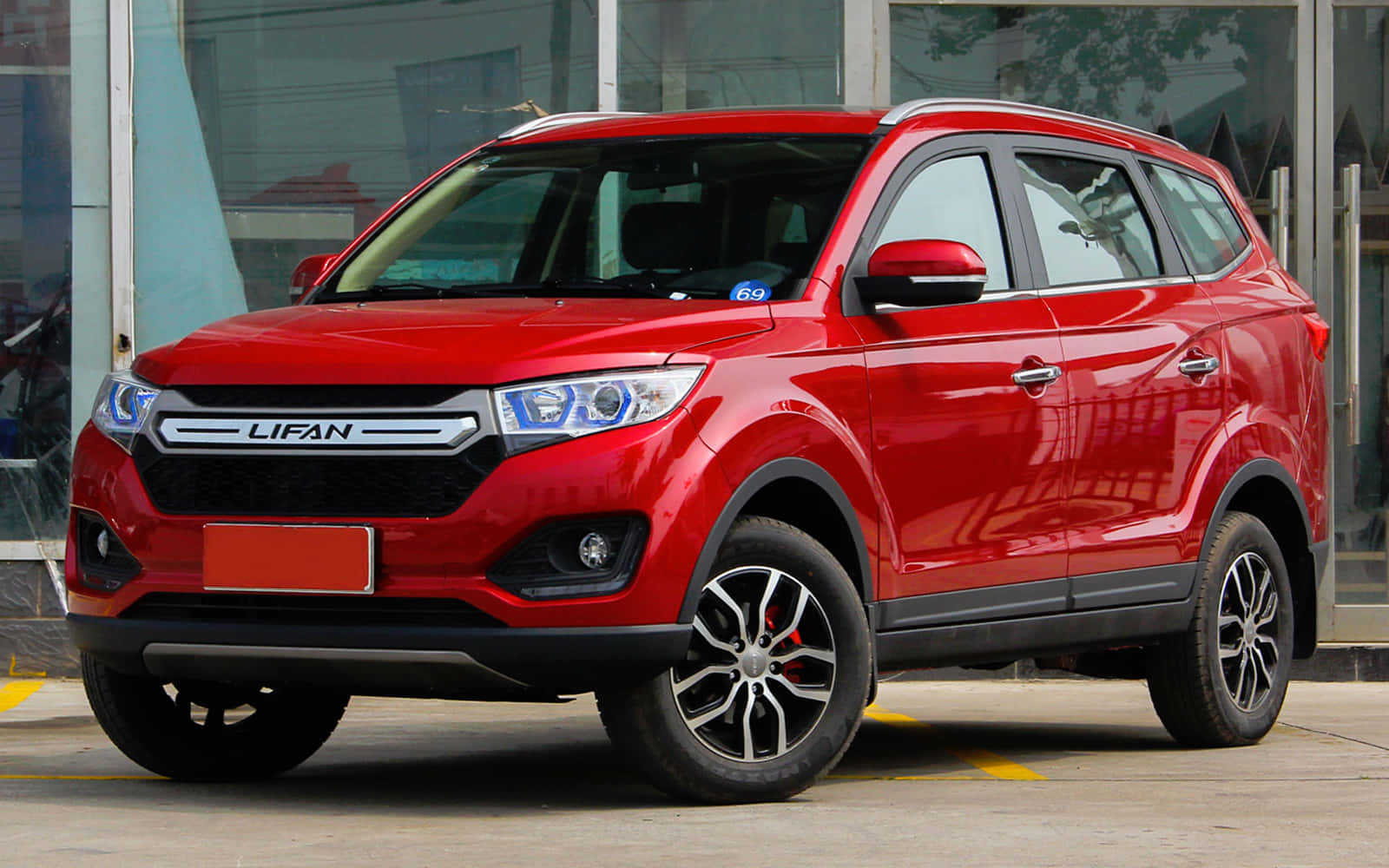 Lifan 桌布 壁紙 — 一架亮紅色嘅Lifan SUV停泊喺玻璃門面嘅經銷商前面，配備現代合金輪圈同銳利頭燈。