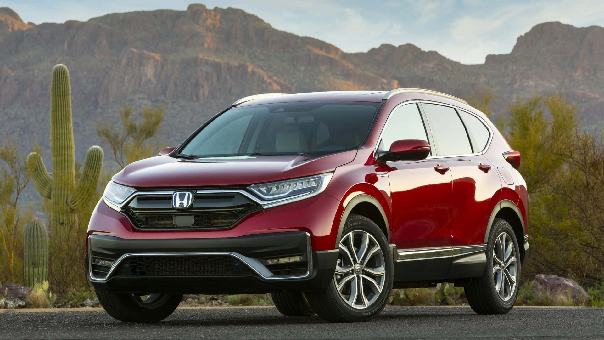 Honda Cr-v 桌布 壁紙 — 一架亮紅色本田CR-V SUV停泊在沙漠道路上，背景有岩石山脈和薩瓜羅仙人掌。