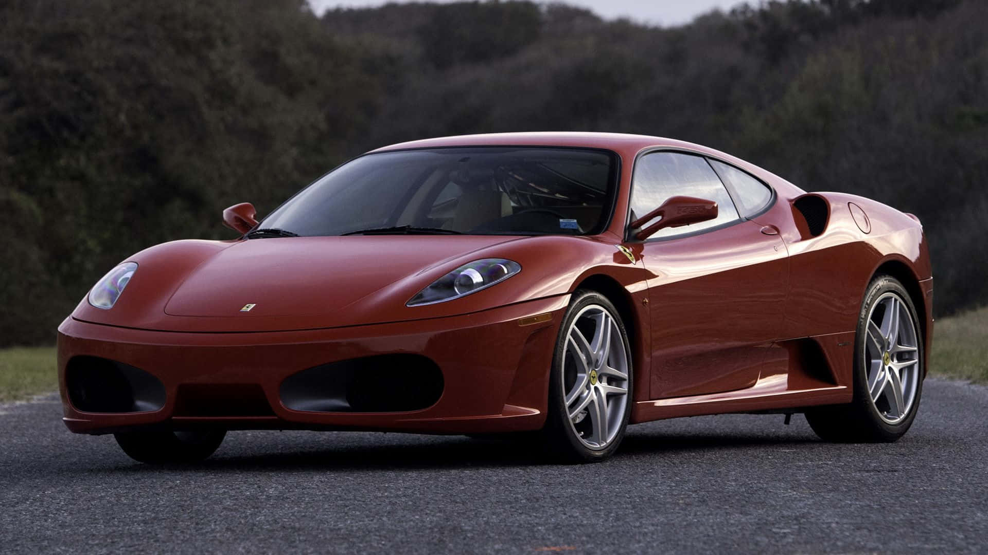 Ferrari F430 桌布 壁紙 — 一架亮紅色法拉利360跑車停泊在鋪砌道路上，背景有模糊的綠色樹木。