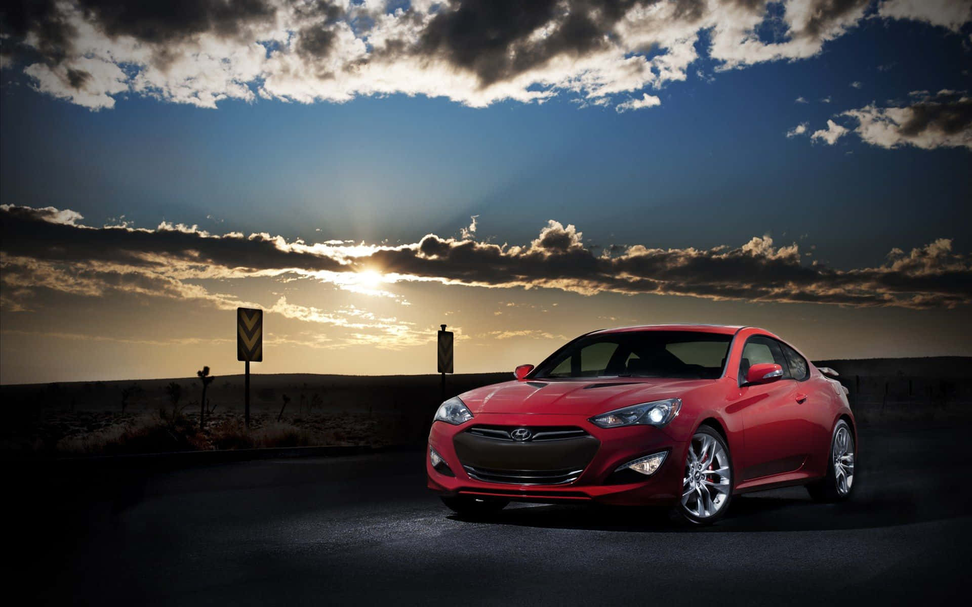 Hyundai Genesis 桌布 壁紙 — 一架亮紅色跑車停在沙漠公路上，背景是帶有雲彩的戲劇性日落天空。