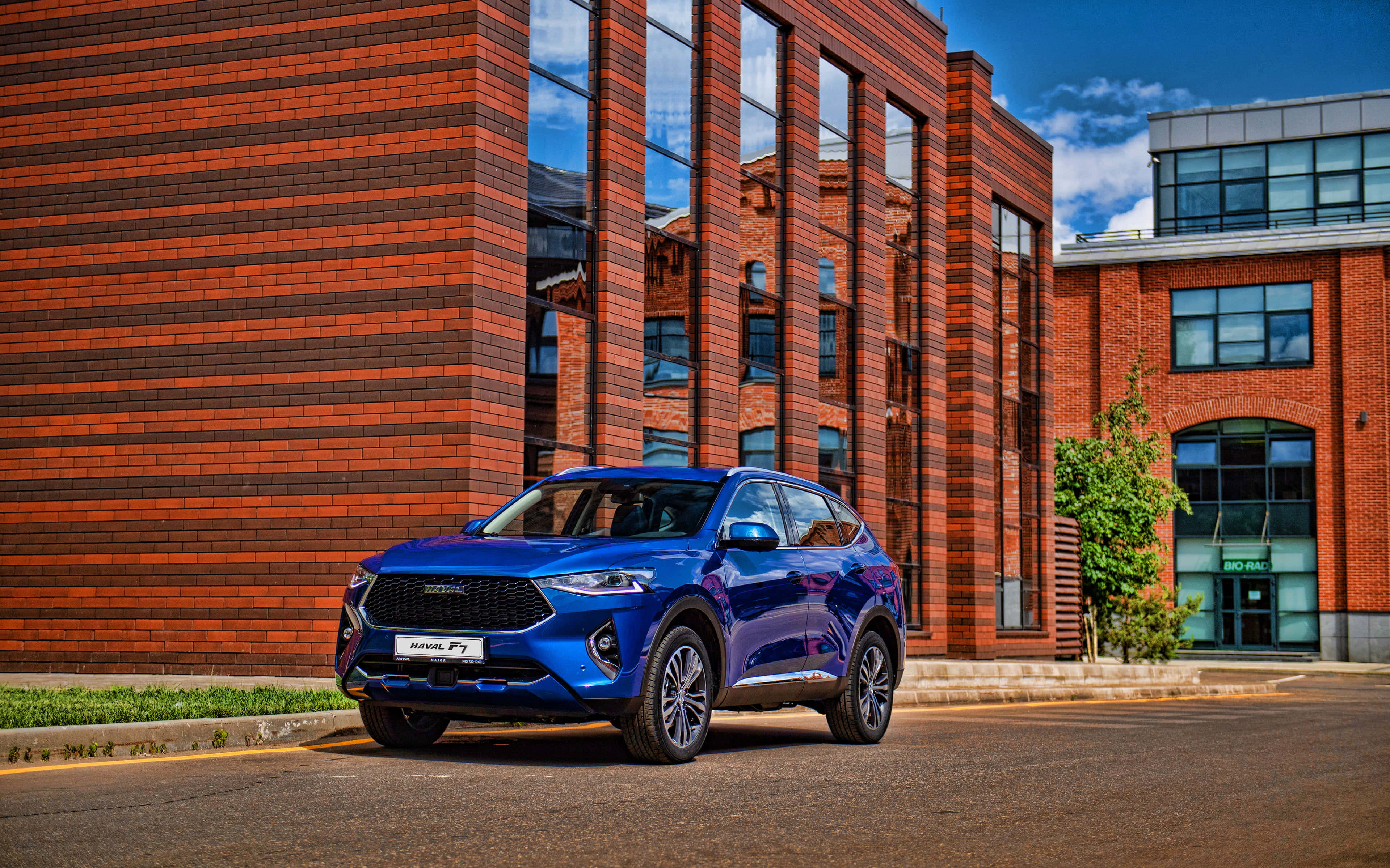 Haval 桌布 壁紙 — 一架亮藍色SUV停喺現代磚砌建築前面，天空晴朗蔚藍。