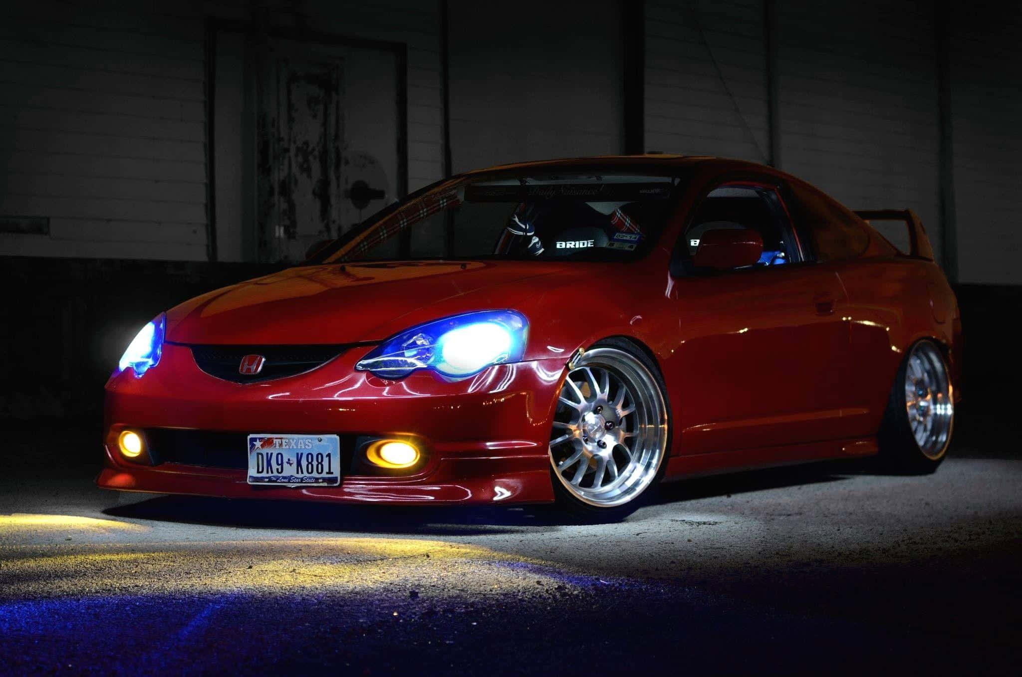 Rsx Type-s 桌布 壁紙 — 一架亮面紅色改裝跑車，帶有發光藍色車頭燈，夜晚停泊在燈光昏暗的車庫中。