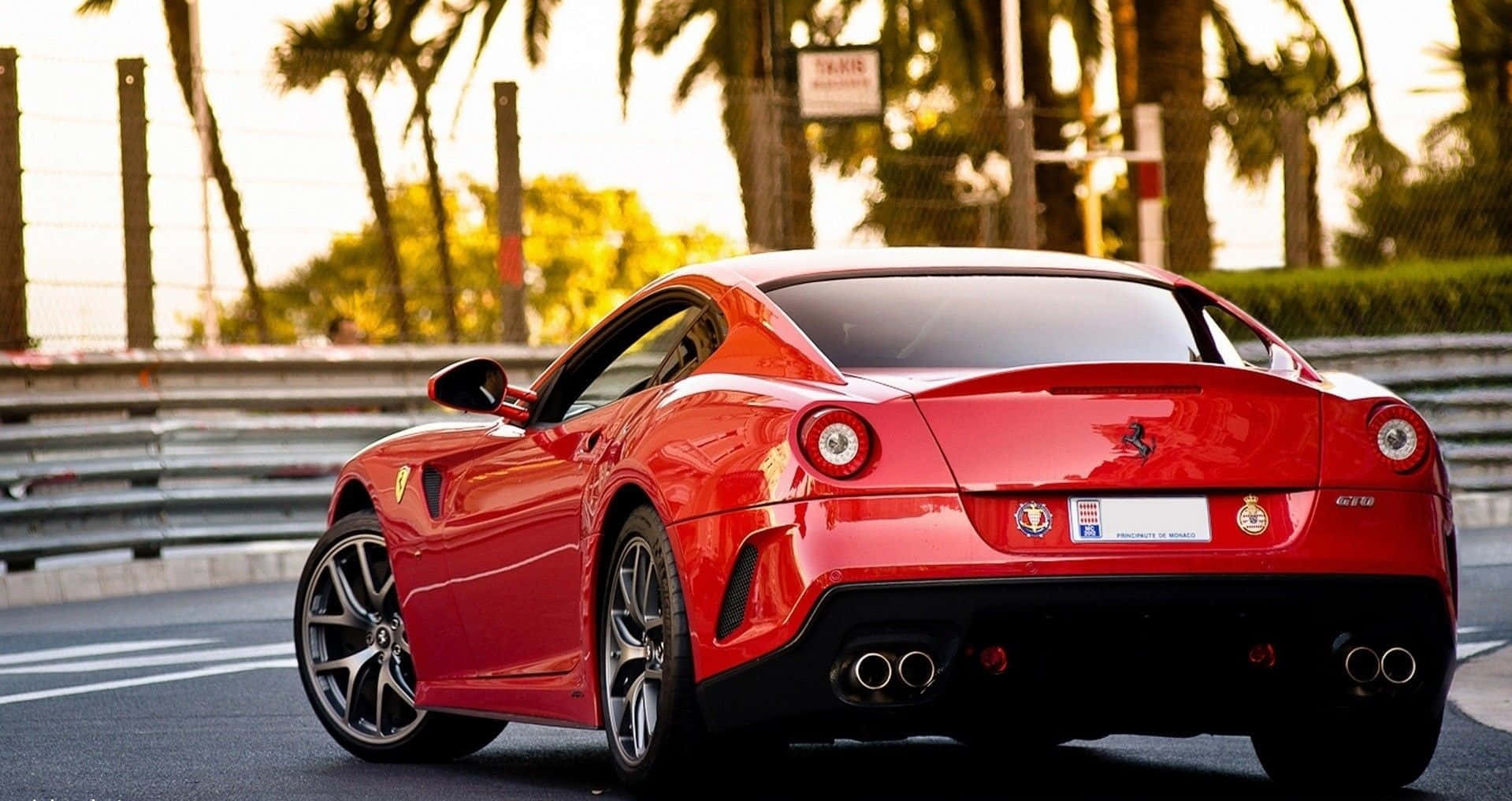 Ferrari 599 Gtb Fiorano 桌布 壁紙 — 一架亮面紅色法拉利跑車停泊在賽車場上，背景有棕櫚樹和日落燈光。