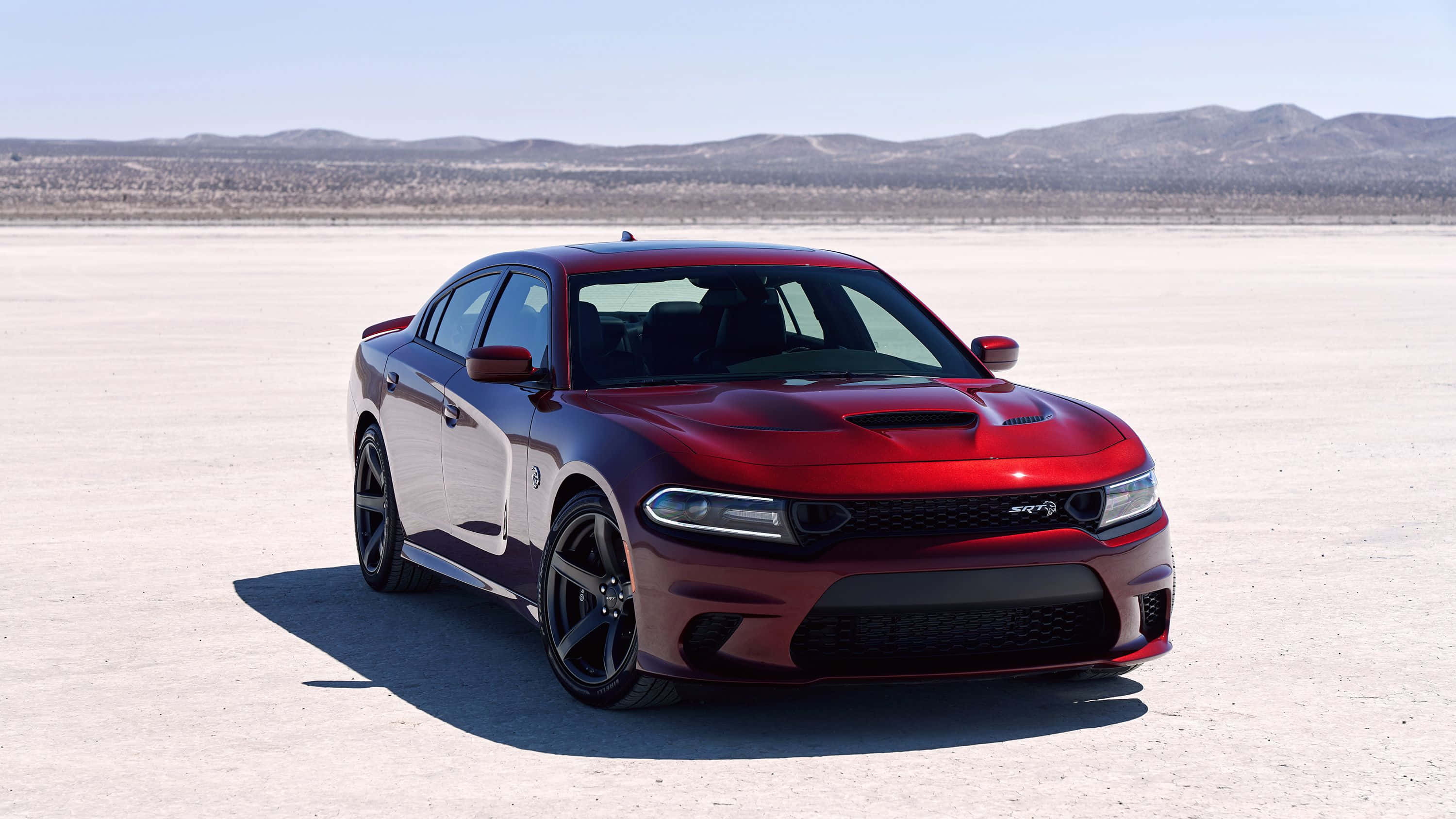 Dodge Charger 桌布 壁紙 — 一架亮麗的紅色 Dodge Charger SRT Hellcat 停泊在廣闊的沙漠鹽灘上，遠方有山脈，天空清澈湛藍。