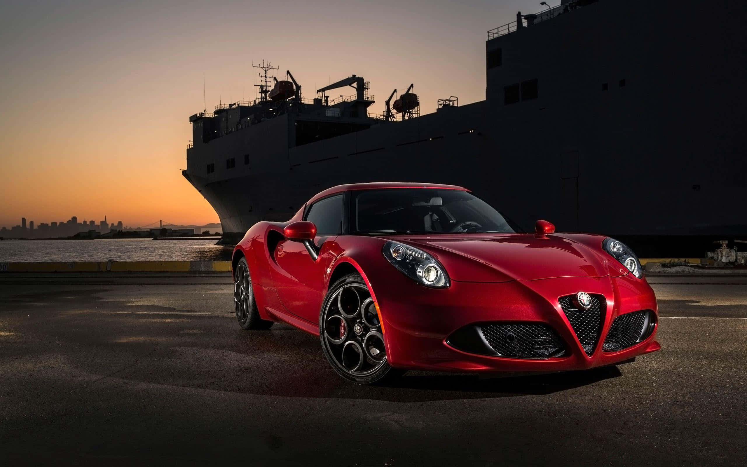 Alfa Romeo 4c 桌布 壁紙 — 一架亮麗的紅色愛快羅密歐跑車在日落時分於港口一艘大型貨船旁閃耀。