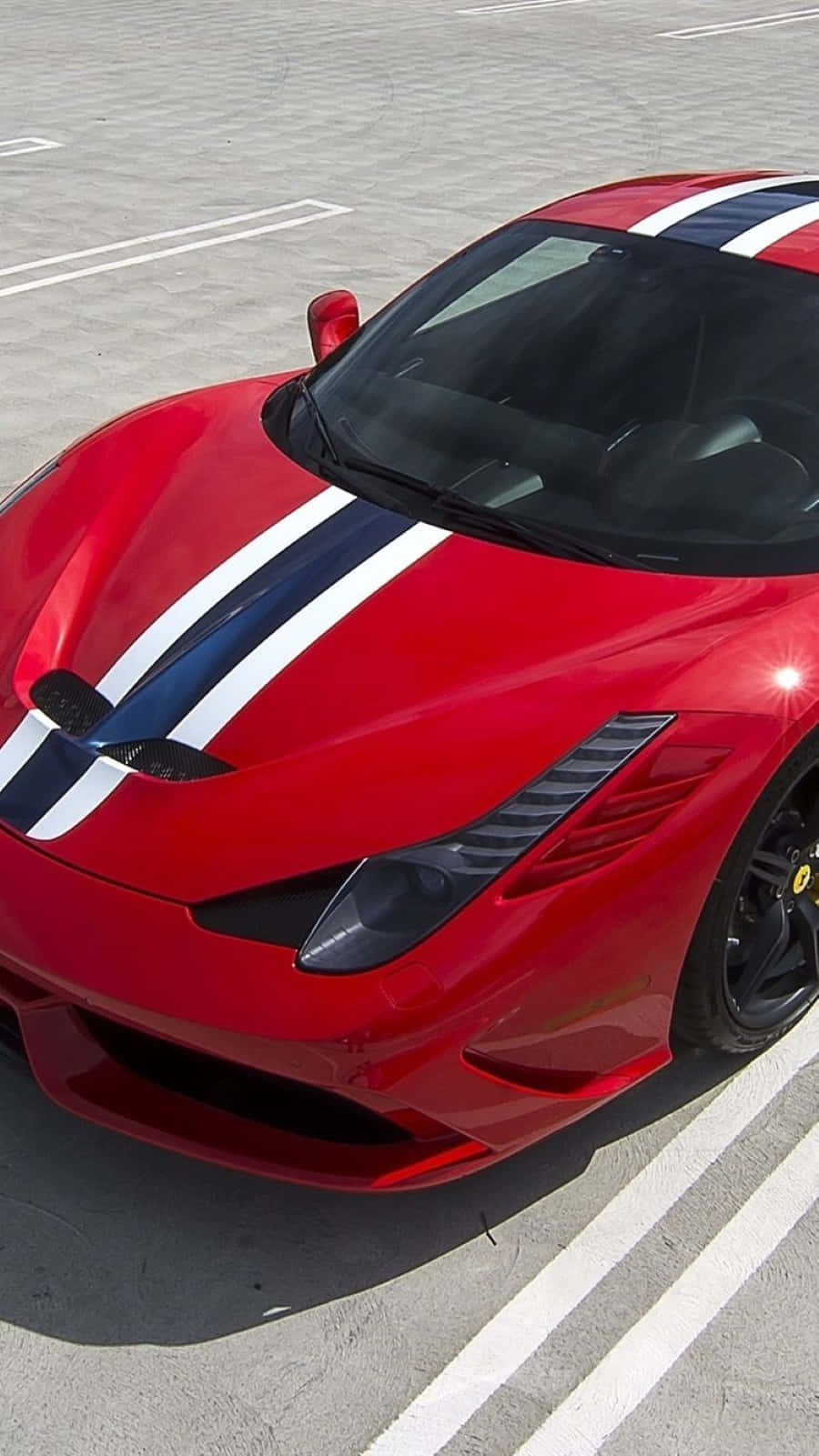 Ferrari 458 Speciale 桌布 壁紙 — 一架亮麗的紅色法拉利跑車，帶有醒目的藍白賽車條紋，停泊在陽光普照的混凝土停車場。