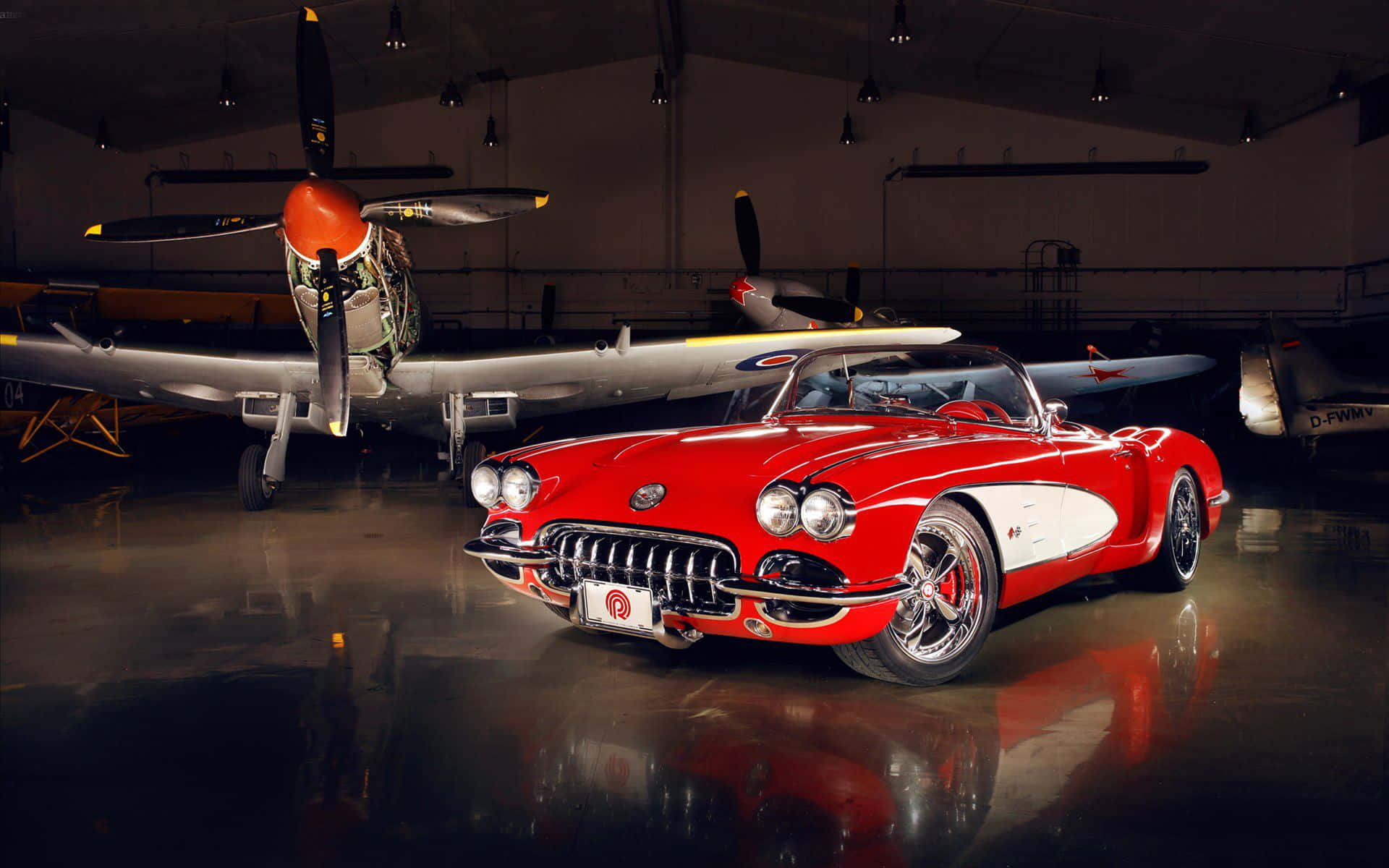 classic 桌布 壁紙 — 一架亮麗的紅色經典Corvette開篷車在昏暗的機庫中，於聚光燈下與復古螺旋槳飛機並列閃耀。