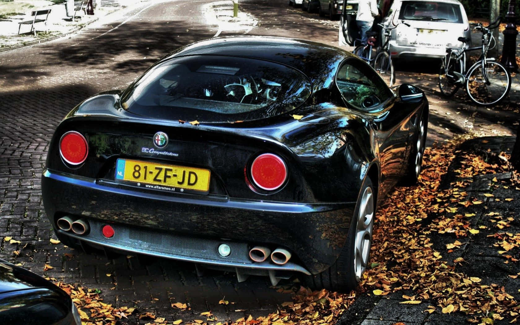 Alfa Romeo 8c Competizione 桌布 壁紙 — 一架亮黑色嘅Alfa Romeo跑車停泊喺散滿落葉嘅鵝卵石街上。