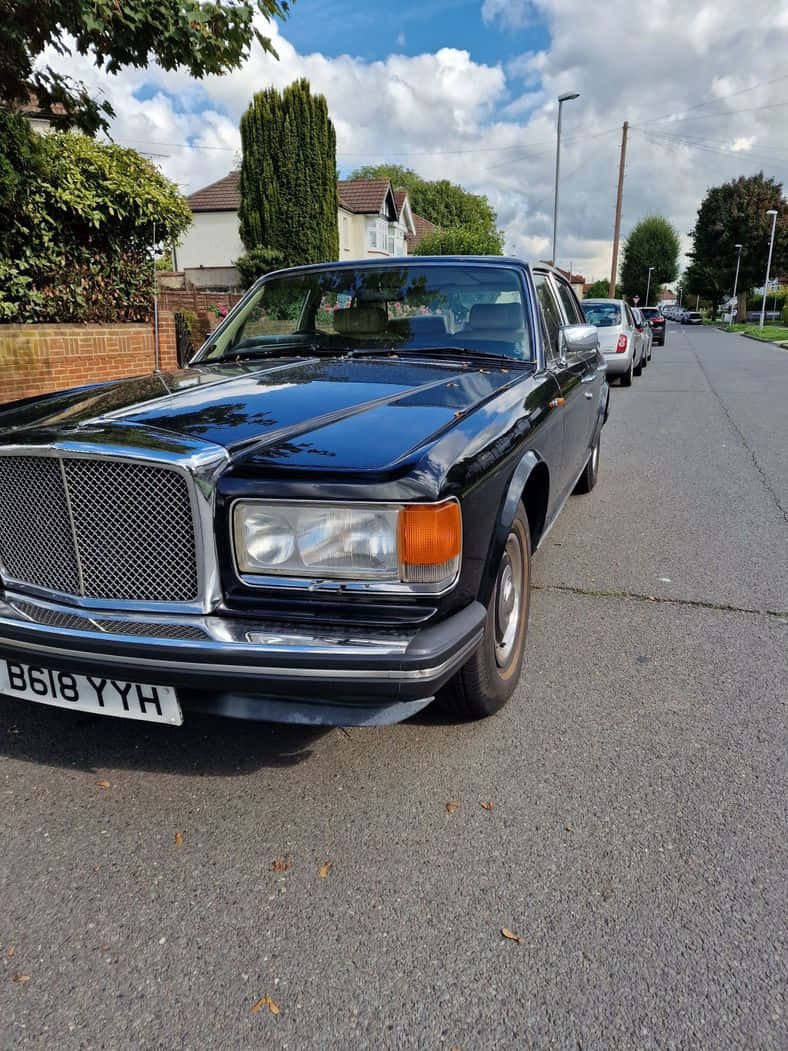 Bentley Eight 桌布 壁紙 — 一架亮黑色賓利T系列轎車停泊在郊區街道上，天空局部多雲。