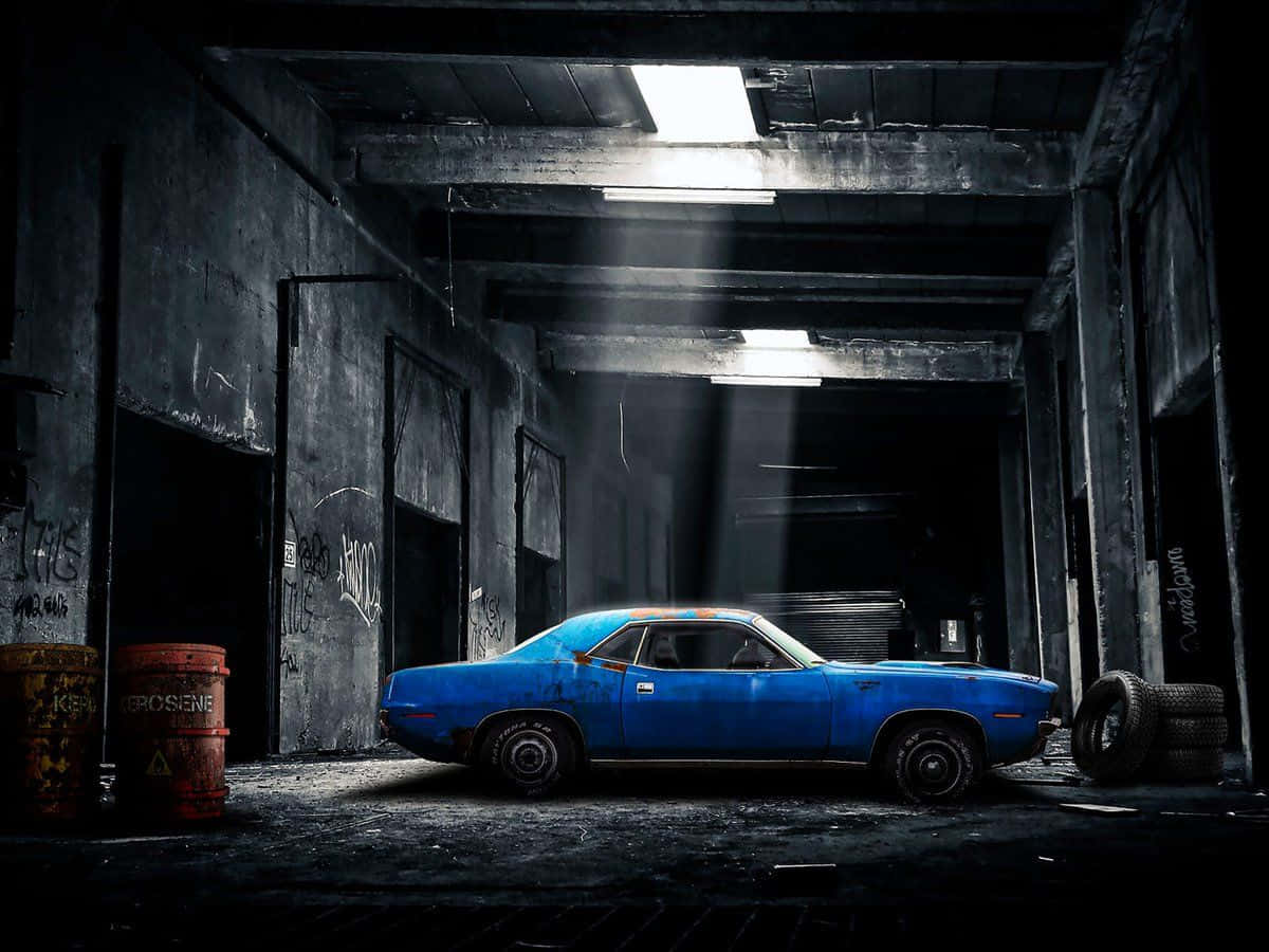 Garage 桌布 壁紙 — 一架充滿活力的藍色經典肌肉車被遺棄在一個骯髒、佈滿塗鴉的倉庫中，沐浴在從上方射來的戲劇性光線中。