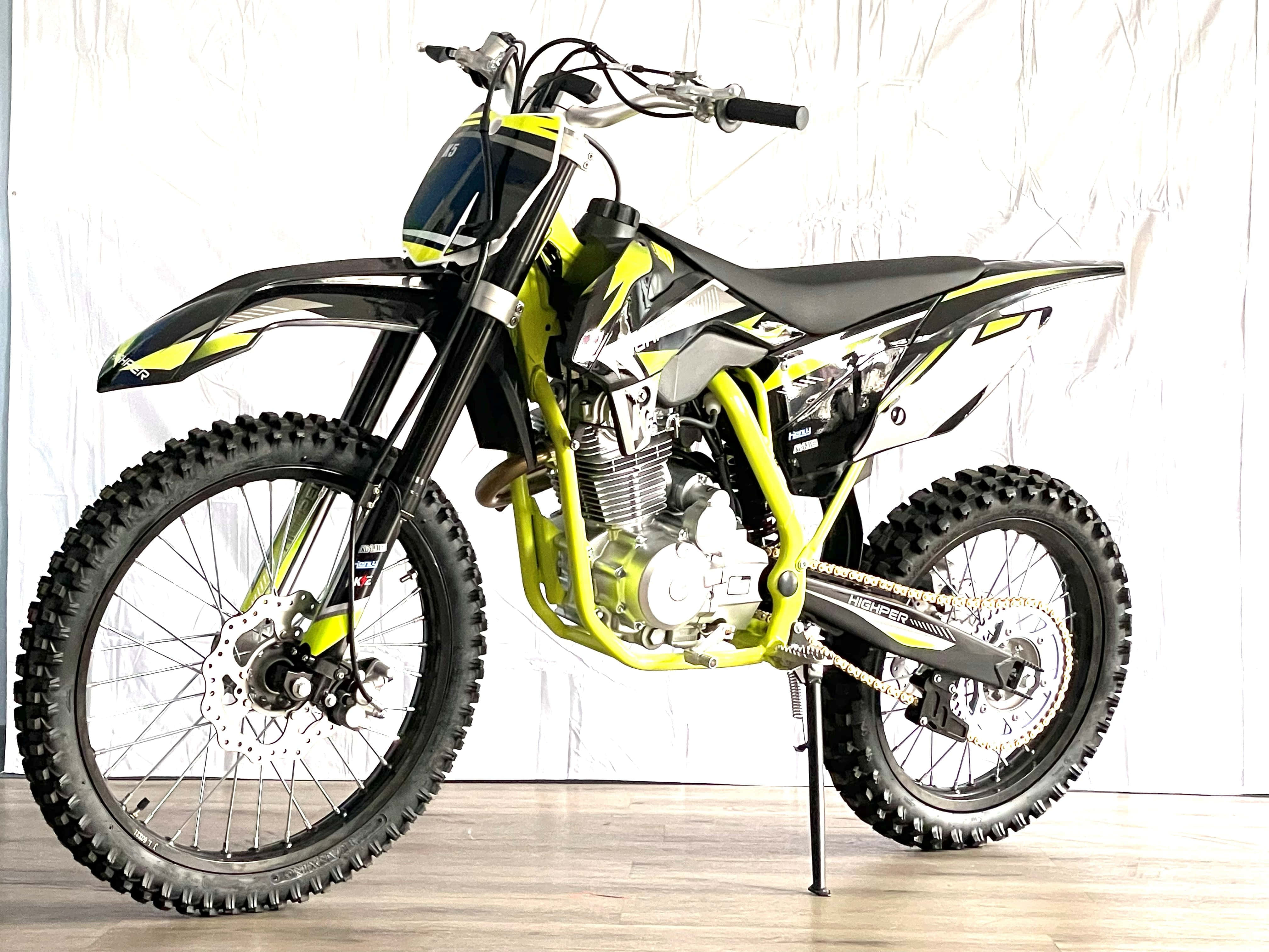 Dirtbike 桌布 壁紙 — 一架充滿活力的青檸綠色和黑色越野電單車，配備防滑輪胎，以側腳架支撐在白色背景前。