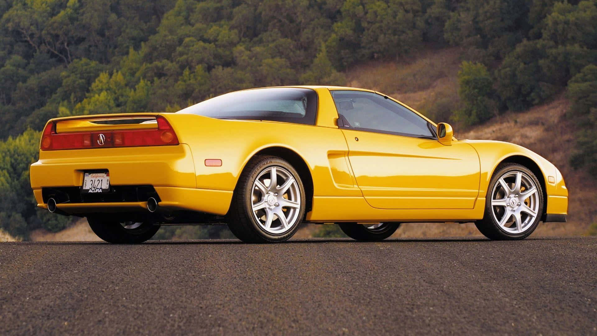 Acura Nsx 桌布 壁紙 — 一架充滿活力的黃色Acura NSX跑車停泊在瀝青路上，背景是樹木繁茂的山坡。