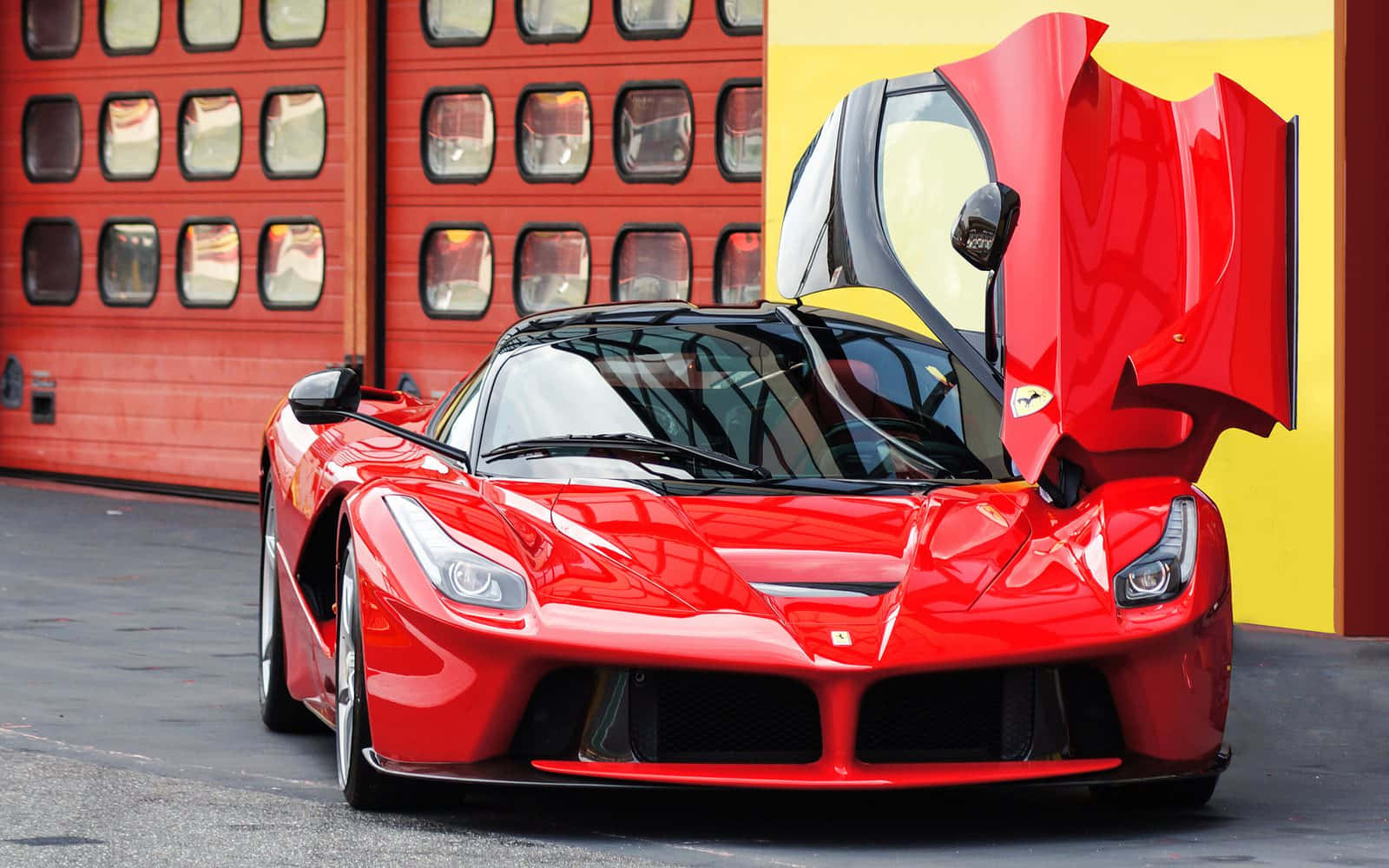 Ferrari Laferrari 桌布 壁紙 — 一架光澤的紅色法拉利LaFerrari跑車，其鷗翼門打開，停在紅色和黃色的車庫門前。