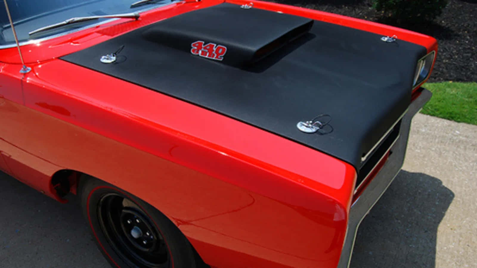 Car Hood 桌布 壁紙 — 一架光澤的紅色經典肌肉車，帶有黑色引擎蓋進氣口和 '340' 標誌，停在陽光明媚的車道上。