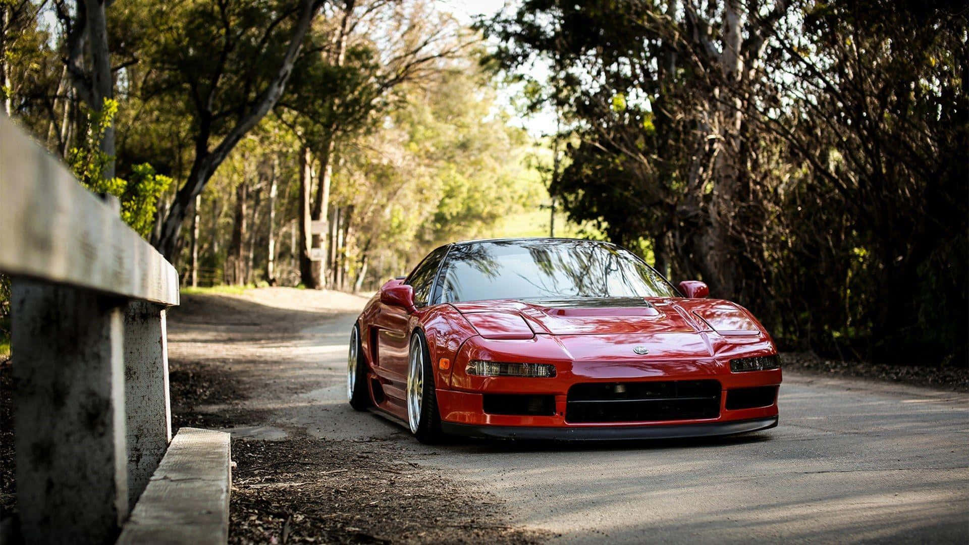 Acura Nsx 桌布 壁紙 — 一架光澤的紅色跑車停泊在林蔭大道上，陽光穿過樹葉灑落。
