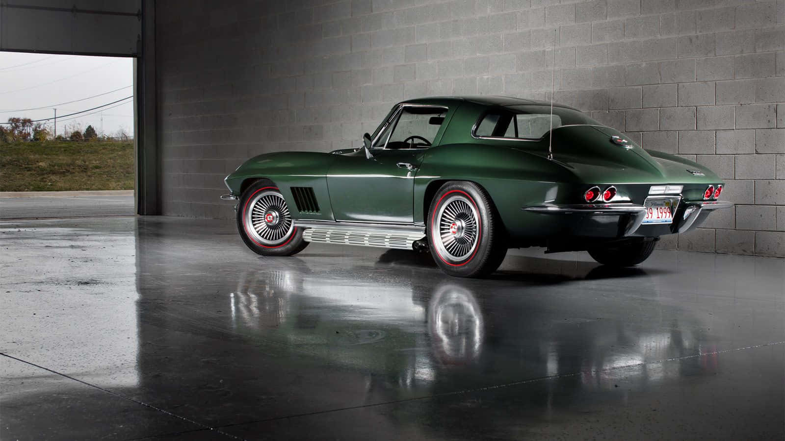 classic 桌布 壁紙 — 一架光澤綠色經典Corvette跑車停泊在混凝土車庫內，其倒影在濕滑的地板上閃爍。