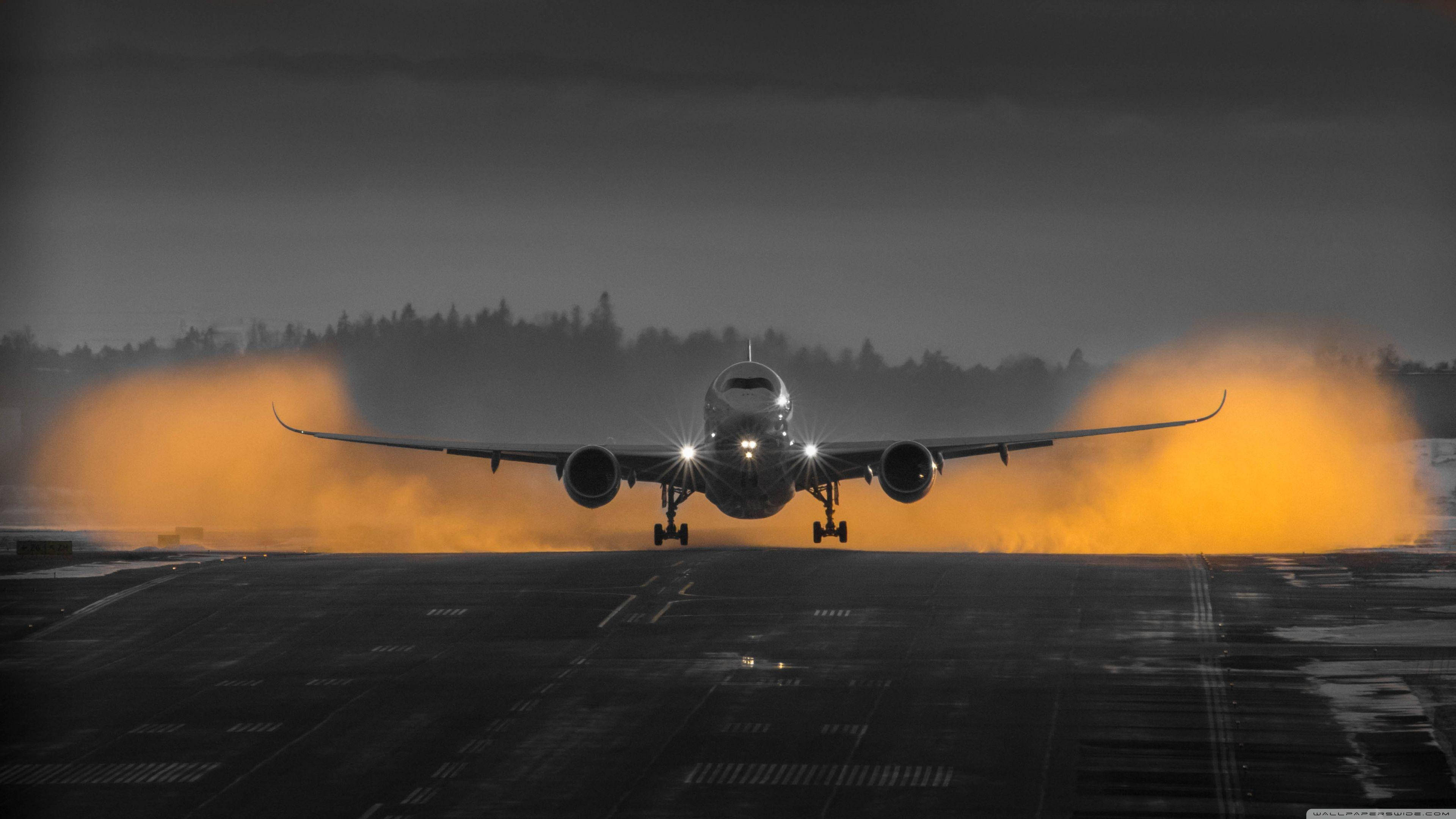 Airport 桌布 壁紙 — 一架商用飛機在夜間降落在潮濕的跑道上，戲劇性的橙色閃光燈照亮了場景。
