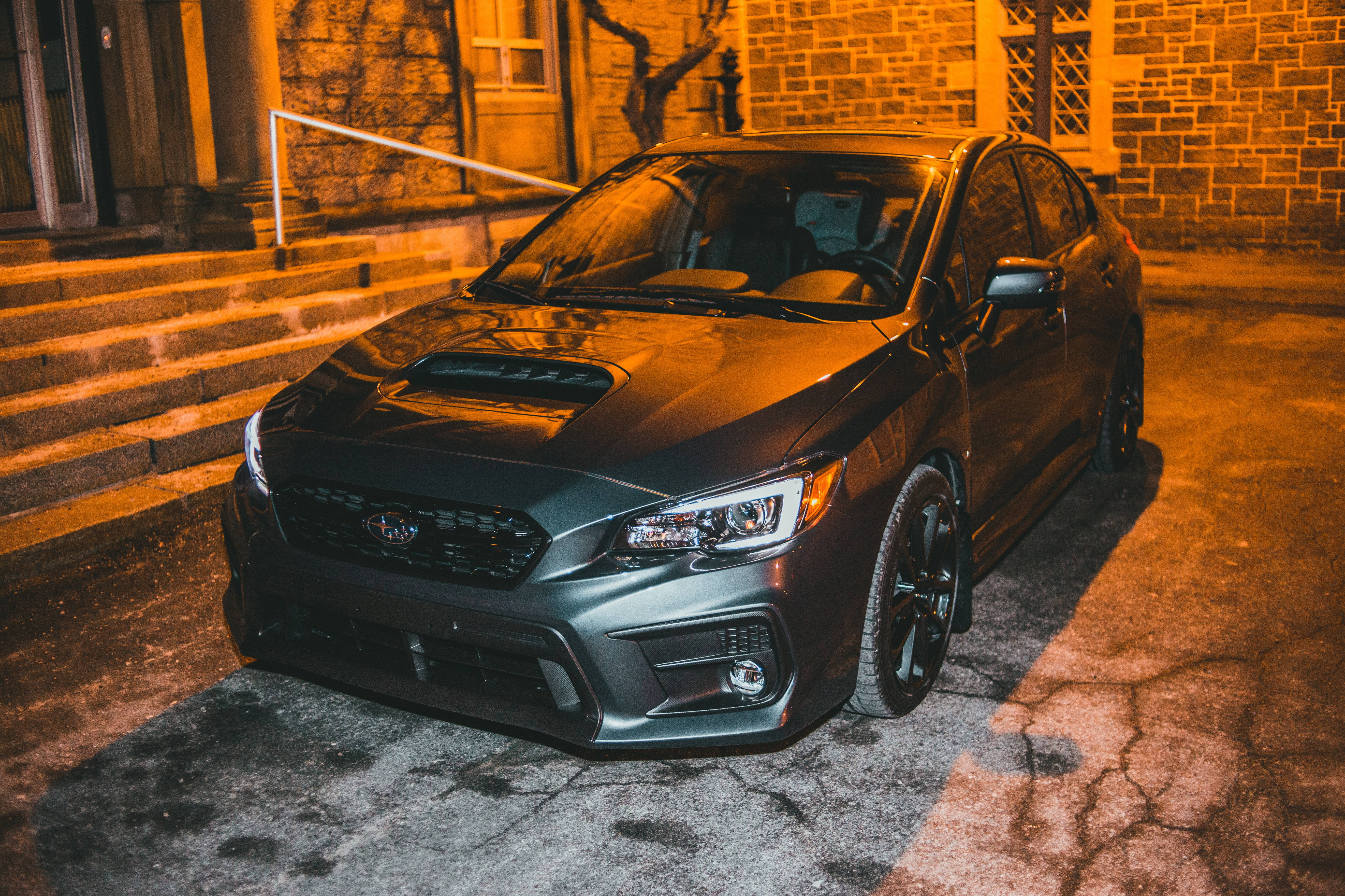 Sports Car 桌布 壁紙 — 一架啞光灰色Subaru WRX夜晚停泊在裂開嘅路面上，被溫暖嘅橙色街燈照射，旁邊係石級。