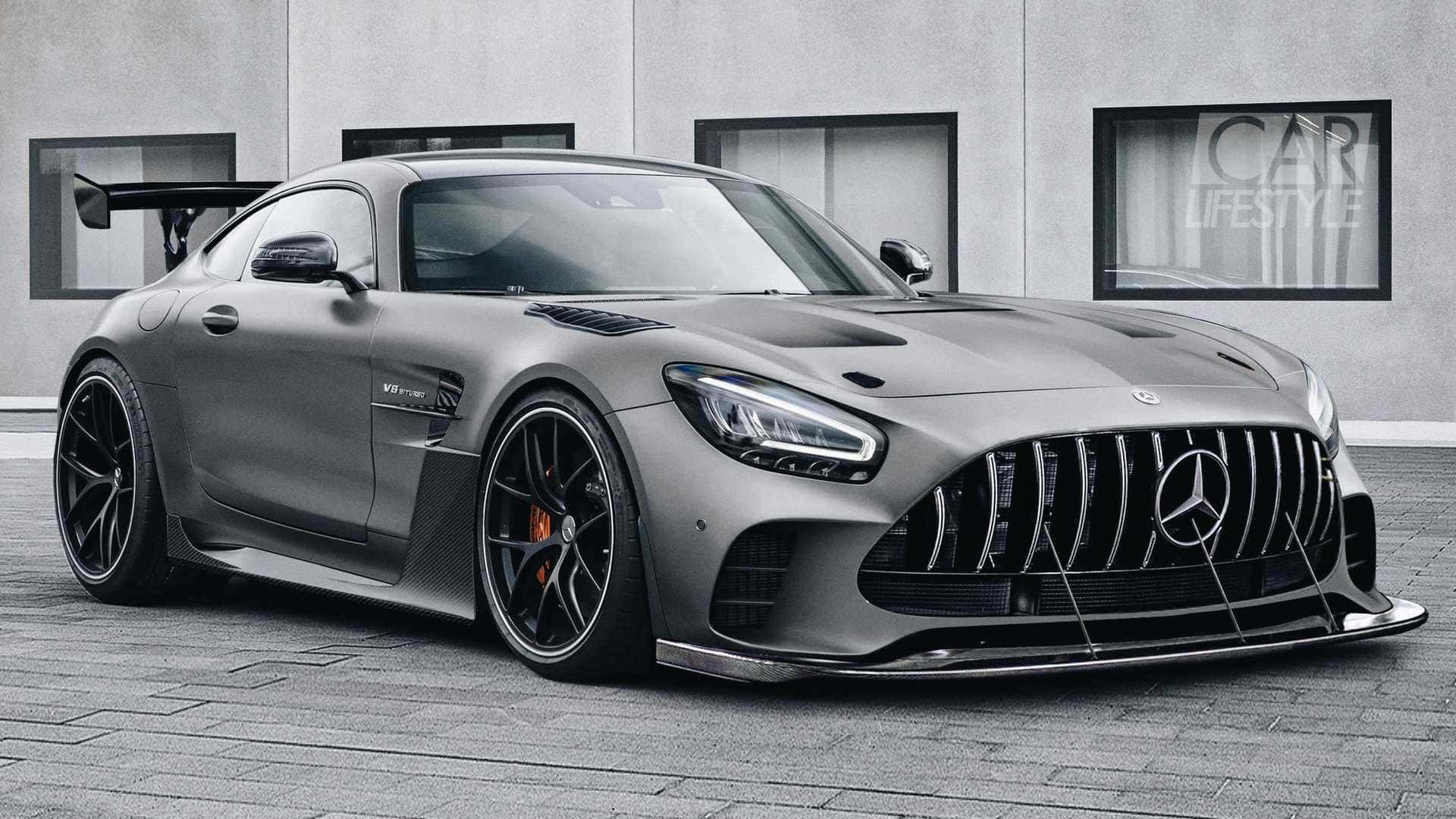 Mercedes Benz Amg Gt 桌布 壁紙 — 一架啞光灰色的 Mercedes-AMG GT R 跑車，配備黑色輪圈和後擾流板，停泊在現代建築物前的瓷磚路面上。