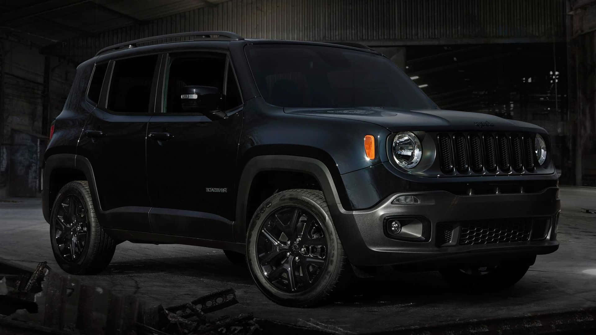 Jeep Renegade 桌布 壁紙 — 一架啞黑色Jeep Renegade SUV在一個粗糙的工業倉庫中，在裸露的橫樑和散落的碎片下被戲劇性地照亮。