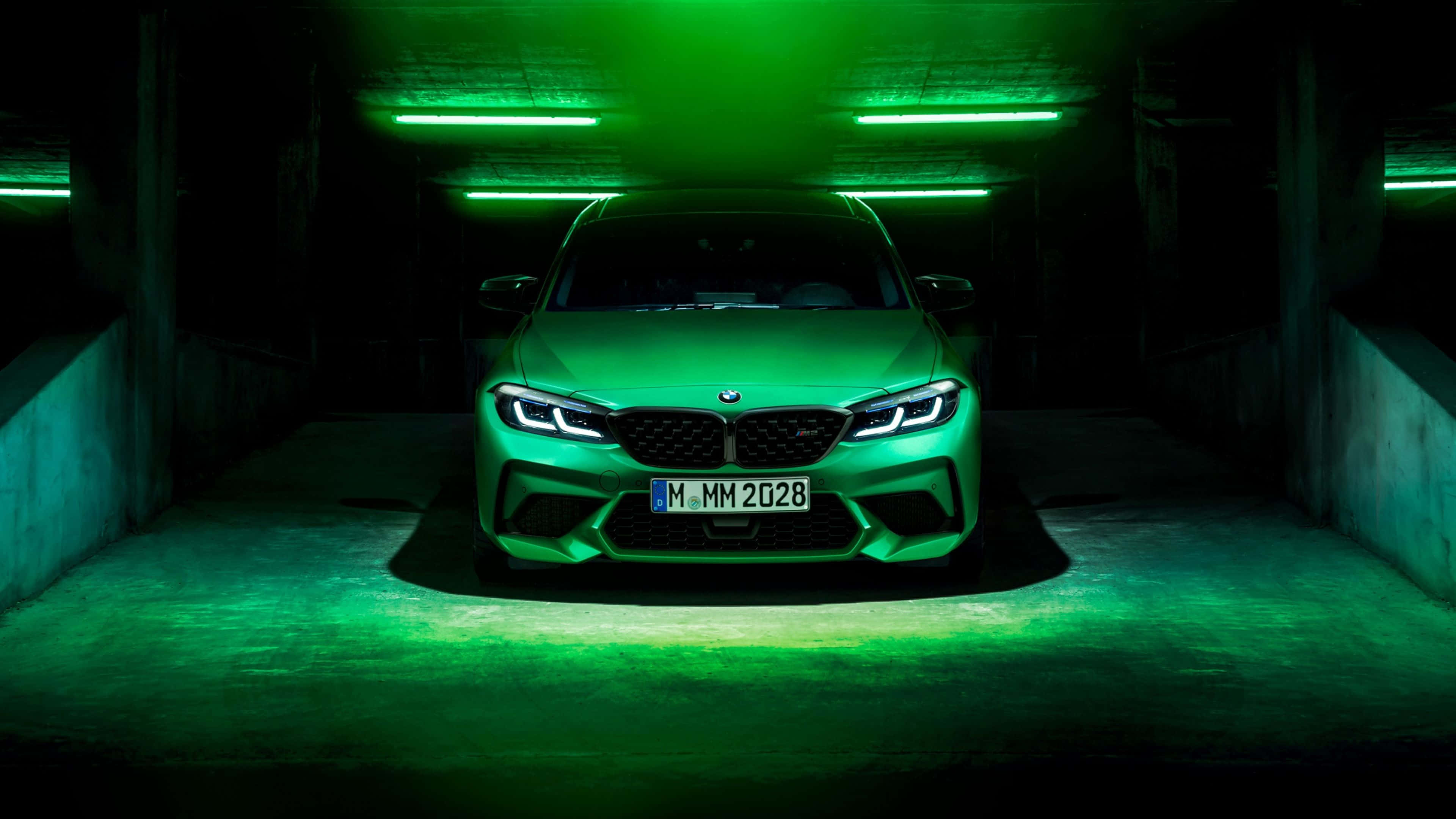 4K BMW 壁紙 桌布 壁紙 — 一架型格綠色BMW M2停泊在燈光昏暗的混凝土車庫中，被天花燈具發出的霓虹綠光籠罩。