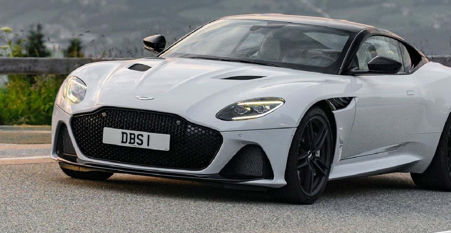 Aston Martin Dbs Superleggera 桌布 壁紙 — 一架型格銀色Aston Martin DBS1跑車停泊在蜿蜒的山路上，背景是翠綠的山丘。